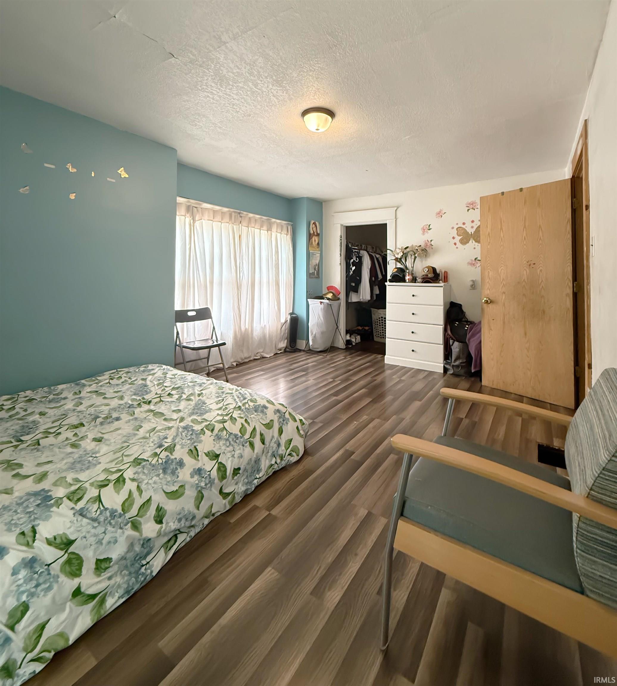 Room featuring wood-finish flooring, a neutral ceiling, and a ceiling-mounted light fixture