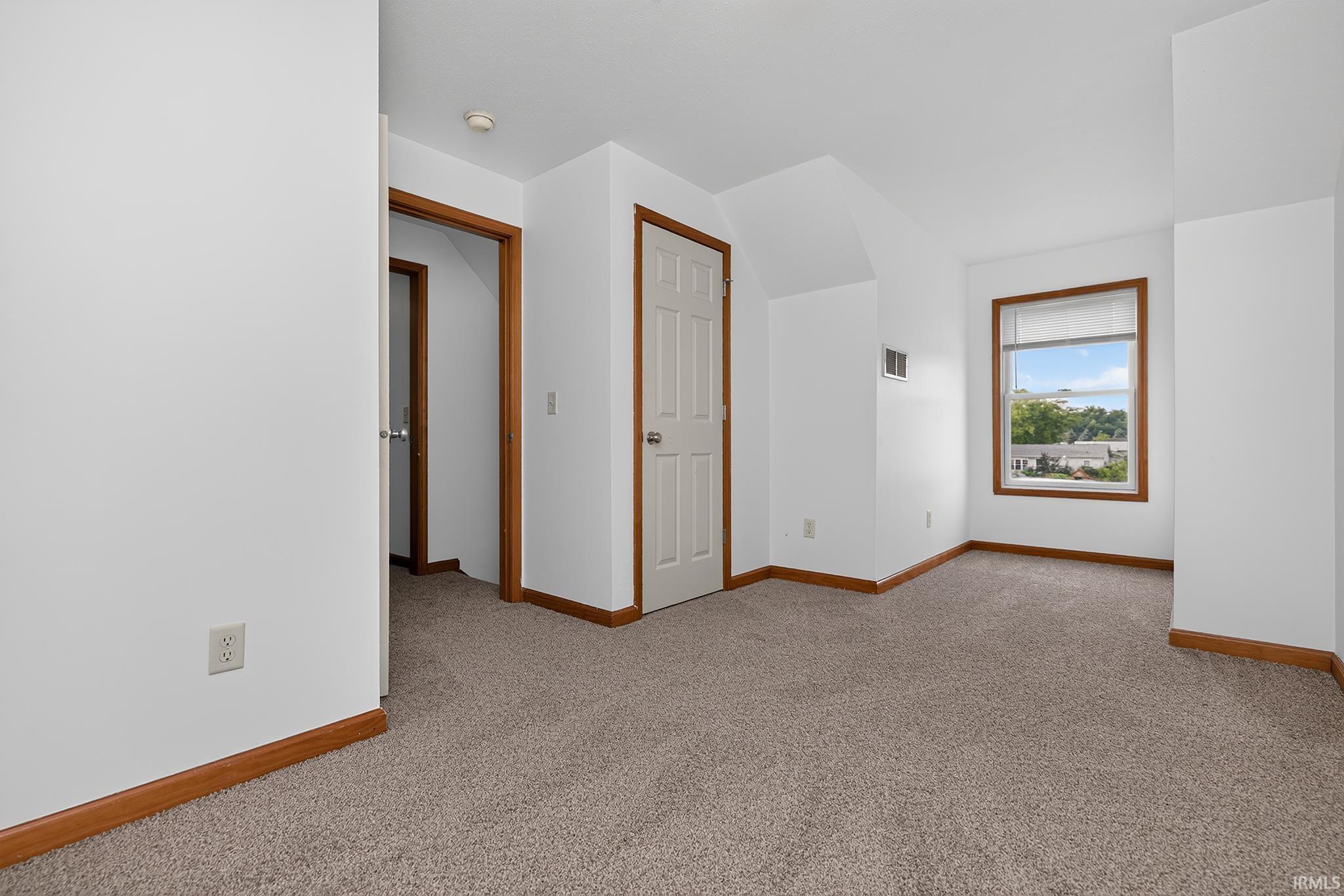 Carpeted room featuring white walls, brown trim, and a window with a white blind