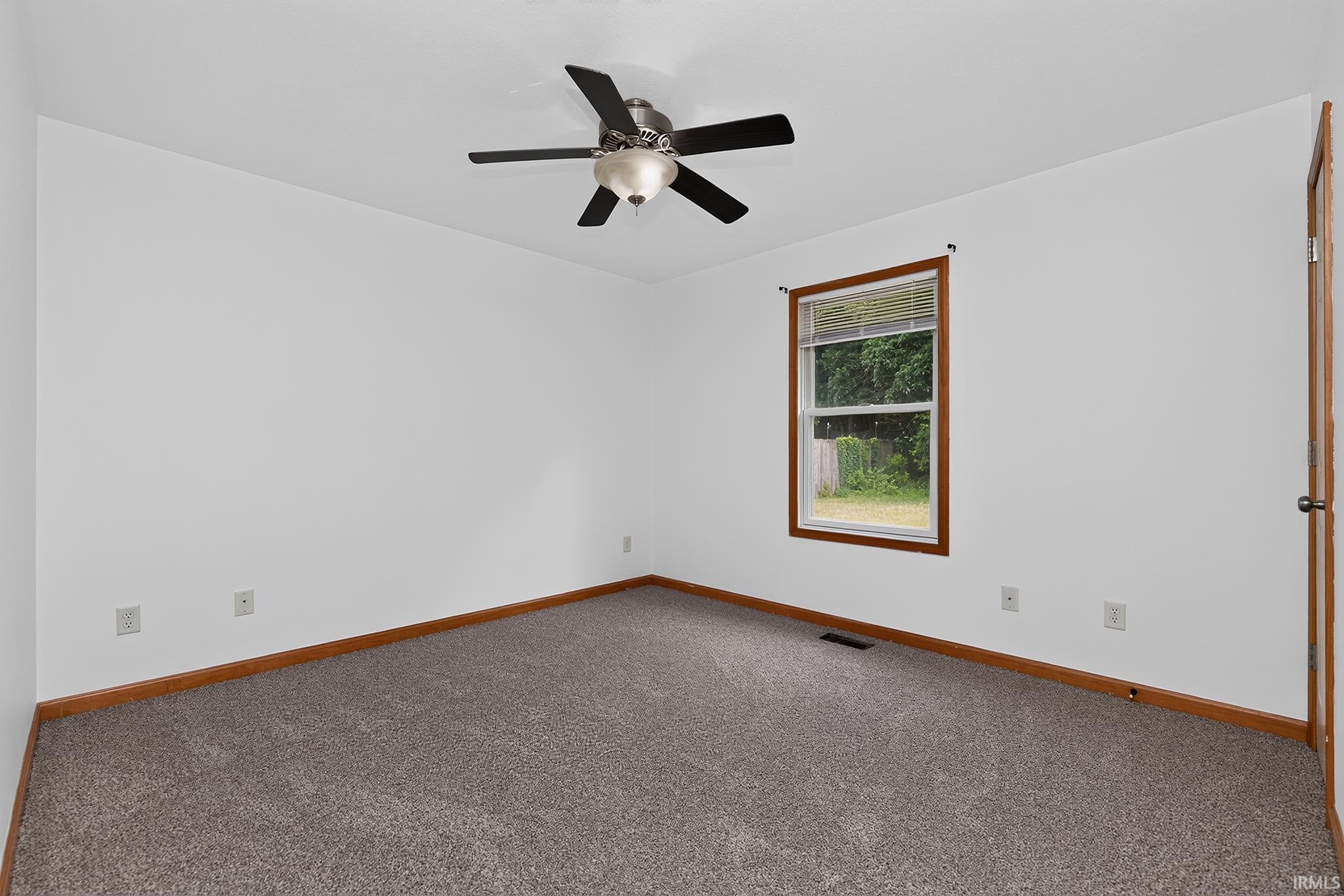 Spacious room featuring neutral carpet flooring, white walls, and wood trim