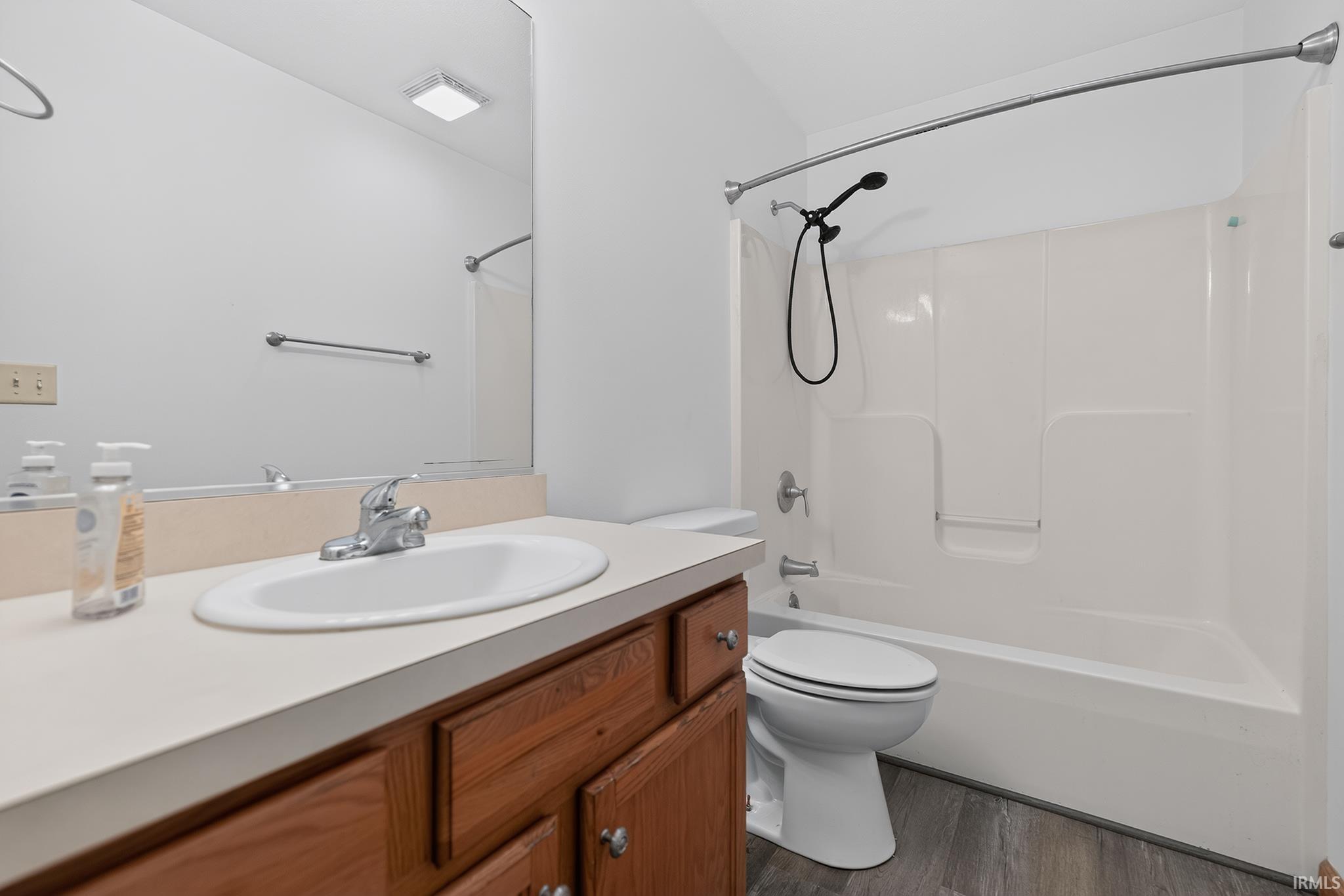 Bathroom featuring a white vanity with a single-basin sink, chrome faucet, and wood-finish cabinetry