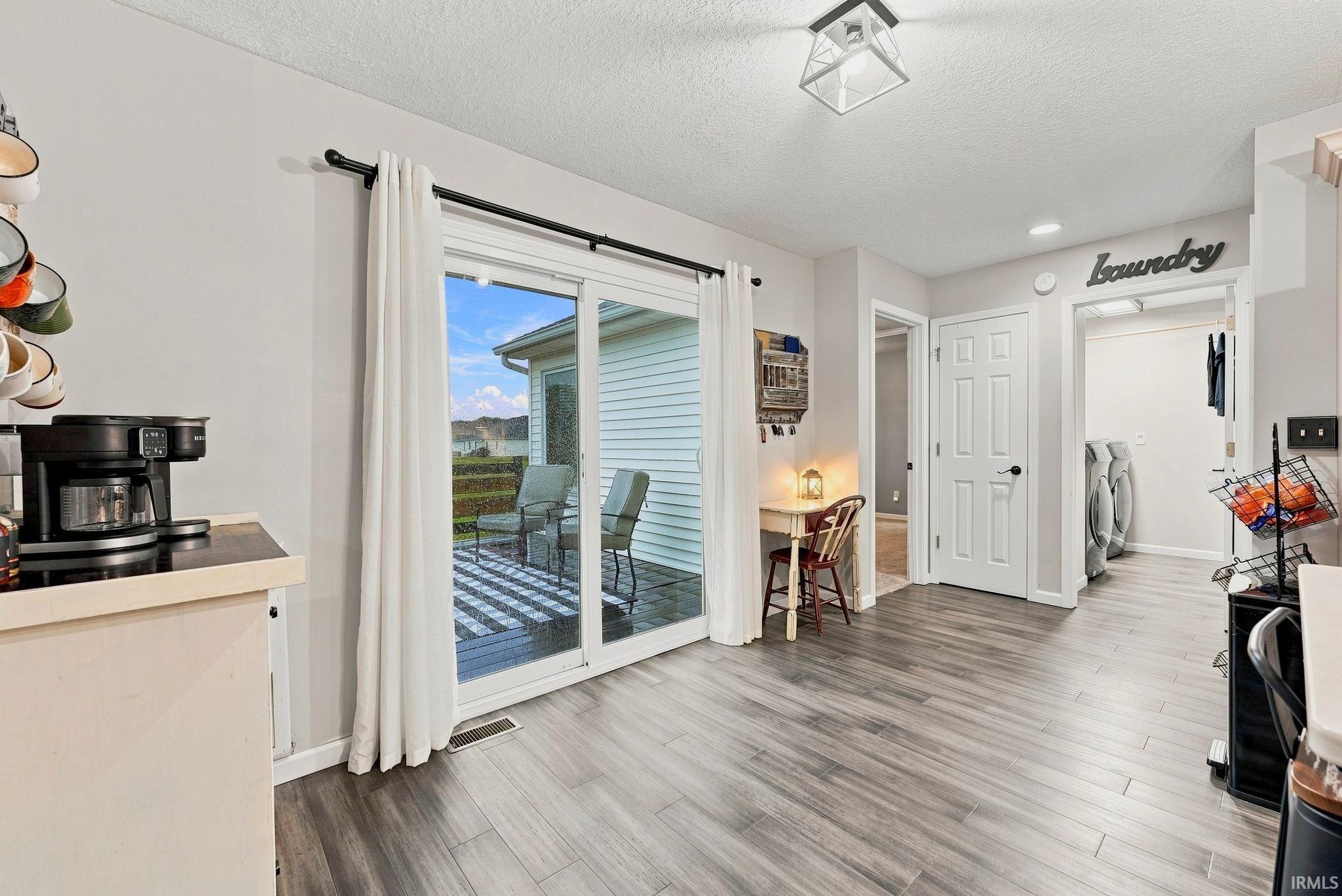Sliding glass door leading to an outdoor deck with a striped rug and partial water scenery
