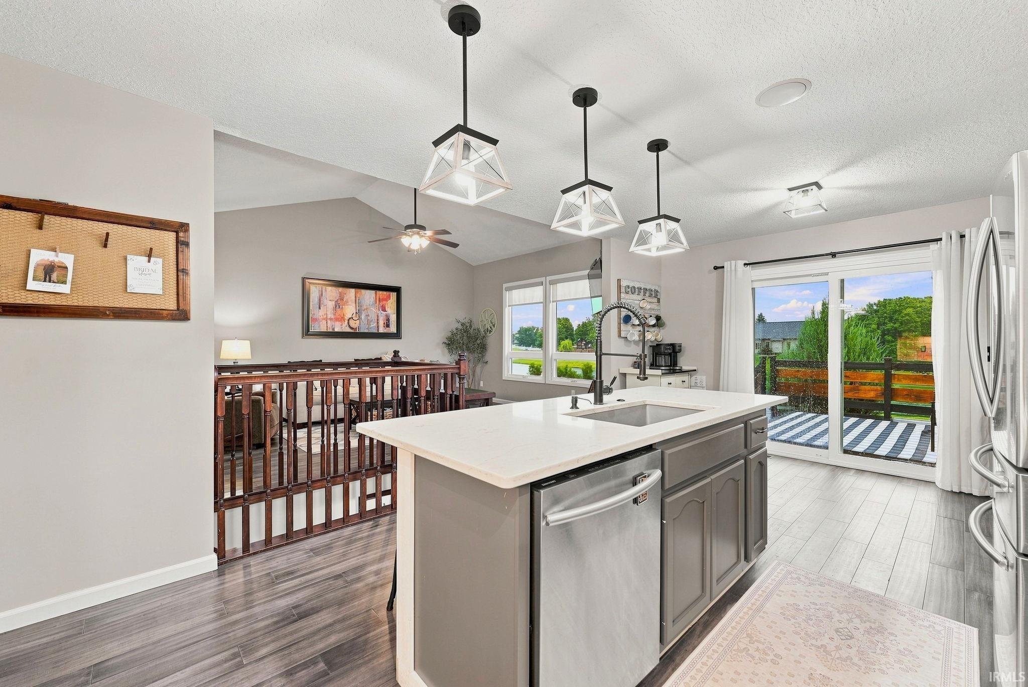 Kitchen island featuring a white countertop, undermount sink with a gooseneck faucet, and integrated dishwasher