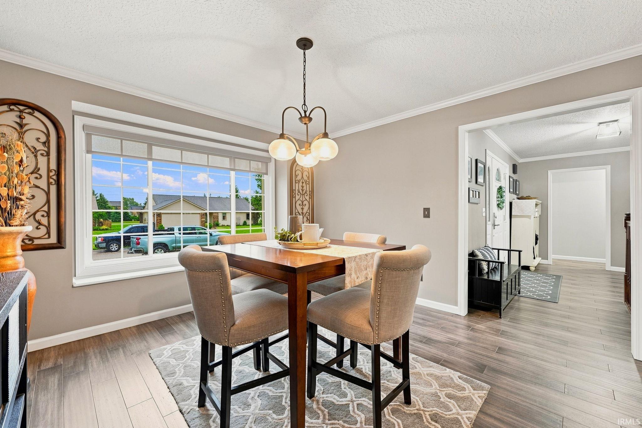 Dining area featuring wood-finish flooring, a large window with white trim, and a three-light pendant fixture