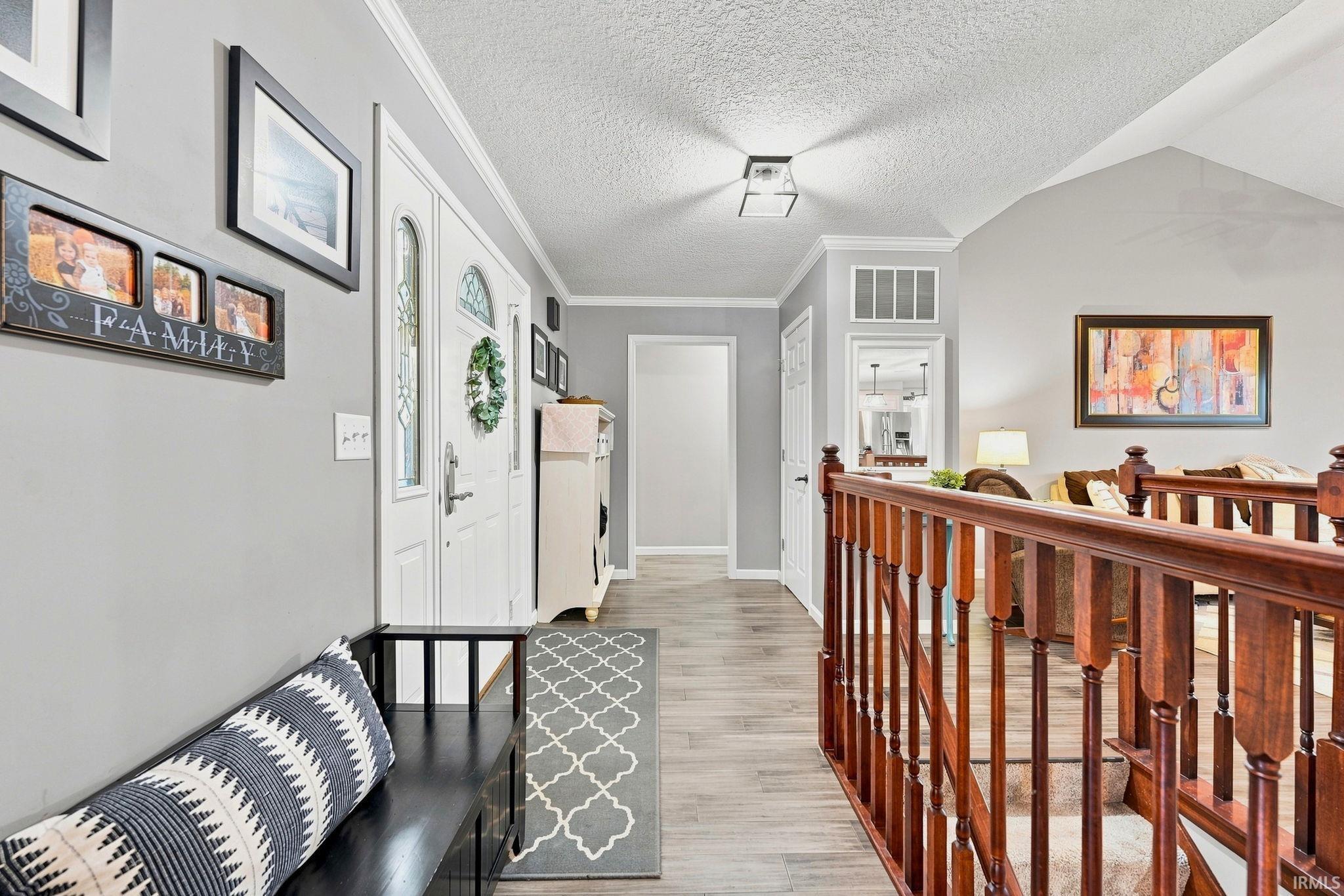 Entryway featuring a white paneled front door with decorative glass, wood-finish flooring, and a vaulted ceiling
