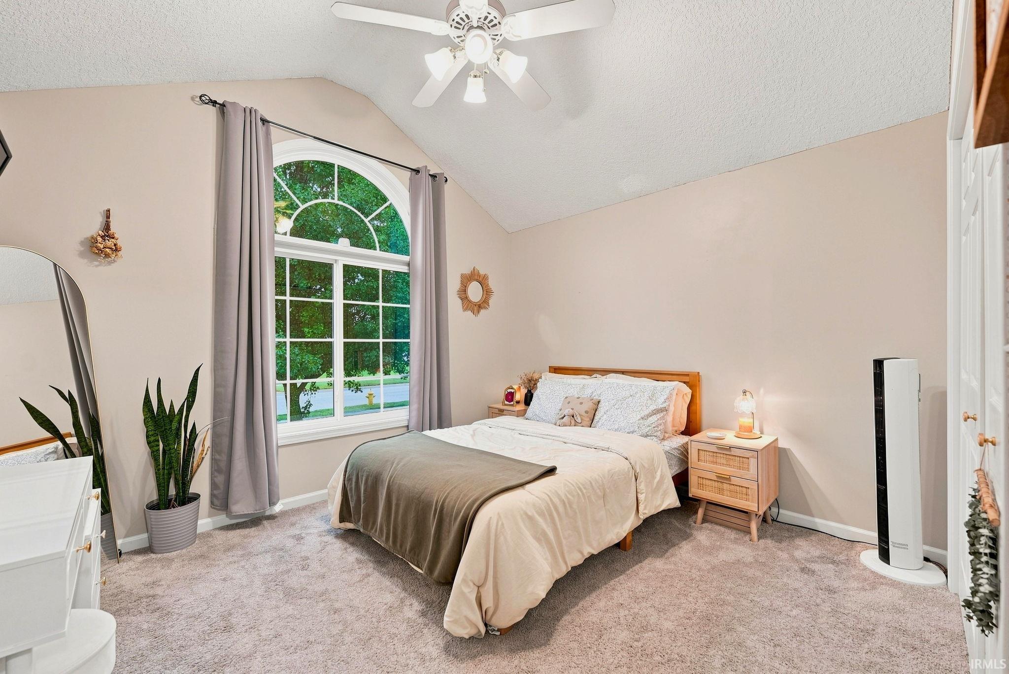 Vaulted ceiling room featuring a large arched window, ceiling fan, and light-toned wall paint