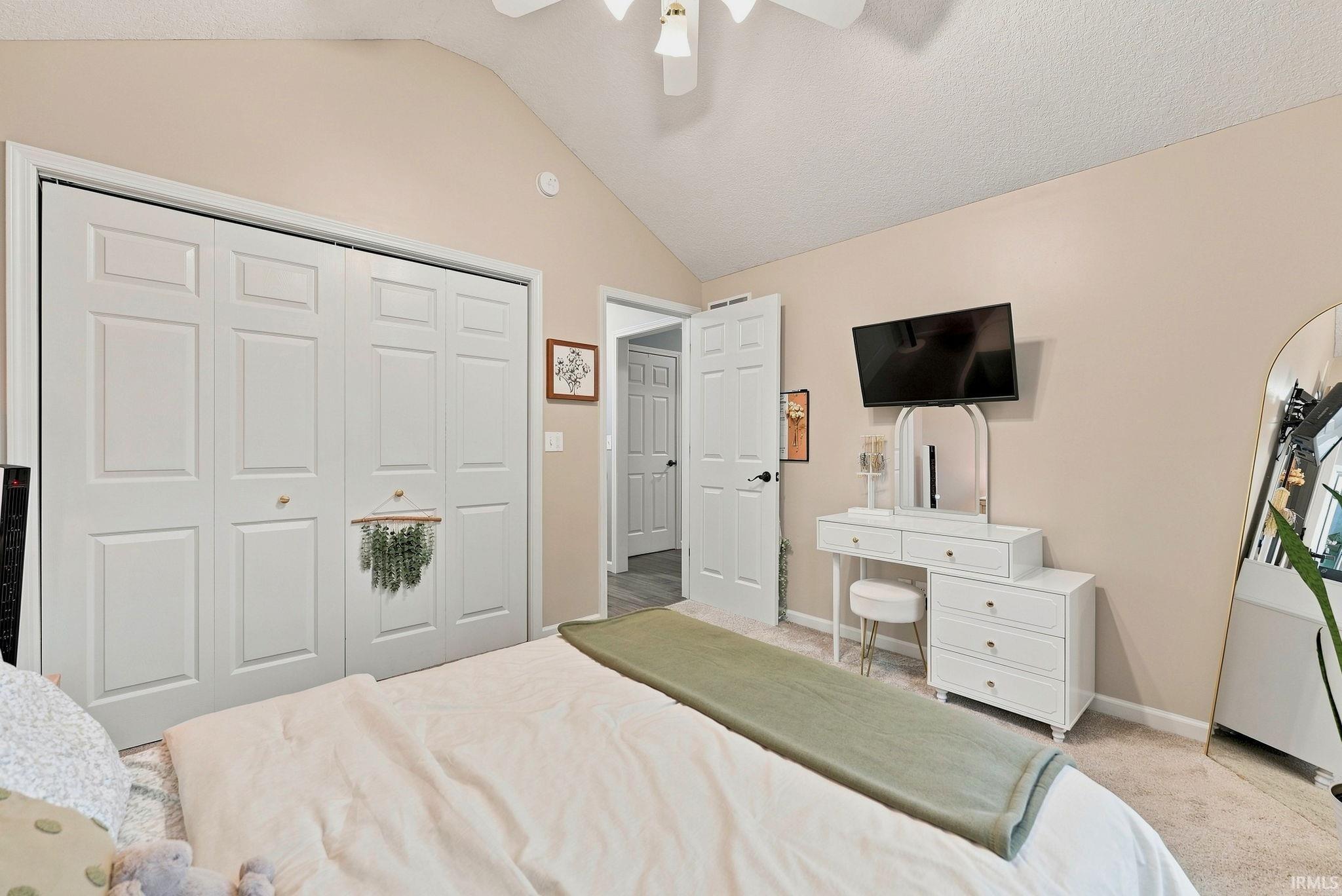 Vaulted ceiling bedroom with neutral wall tones and carpeted flooring