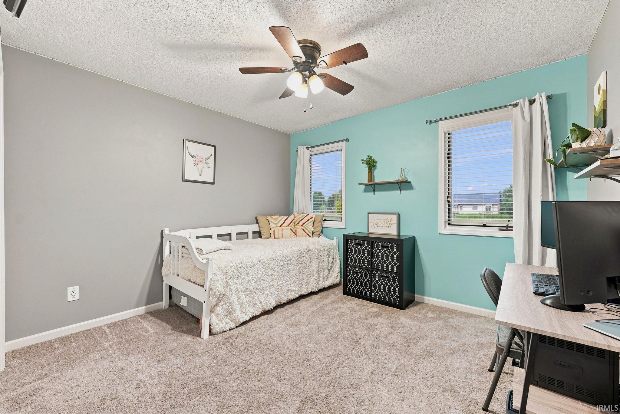 Carpeted room featuring a ceiling fan with light fixture