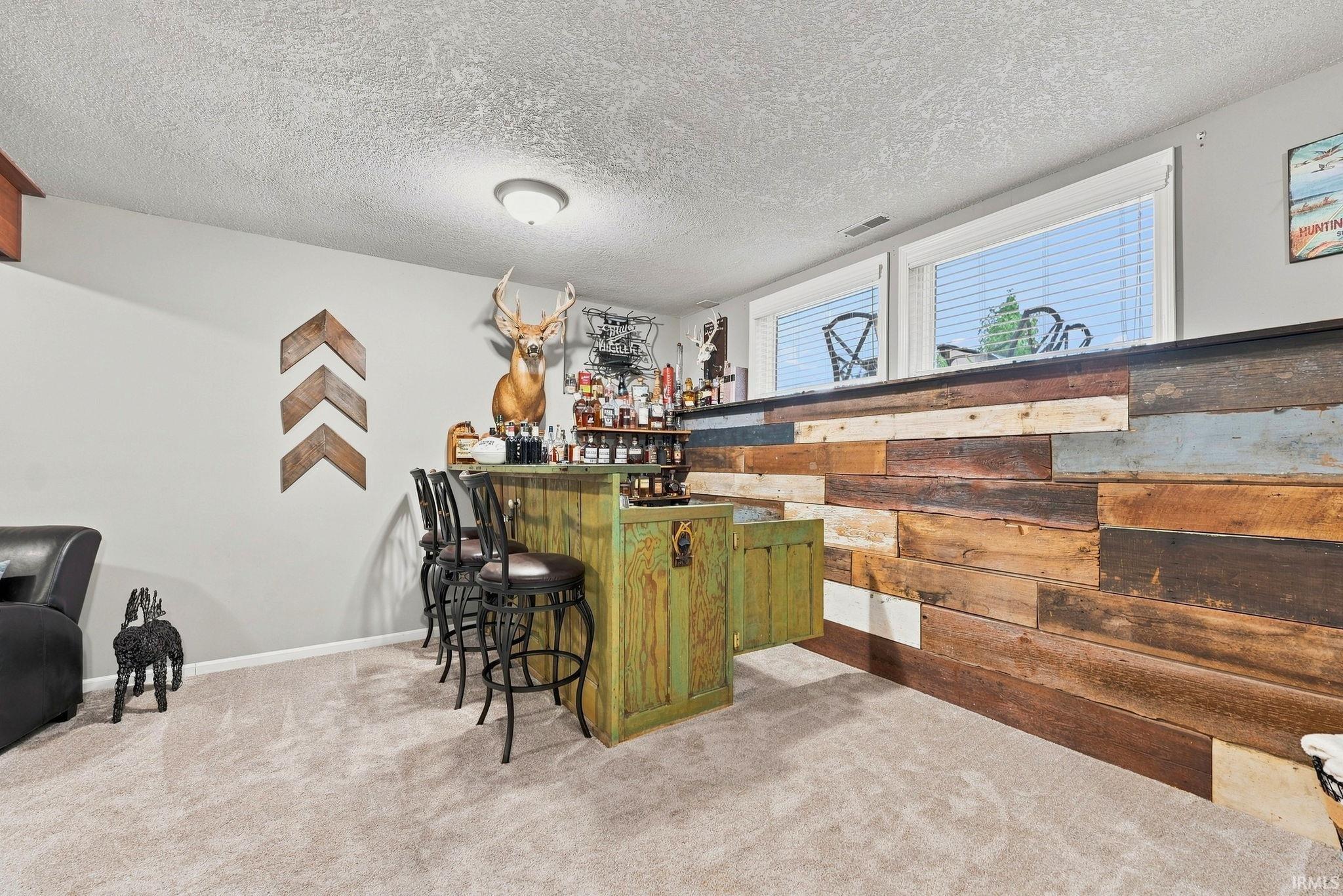 Custom built-in bar with a distressed green finish, complemented by a reclaimed wood-paneled bar face