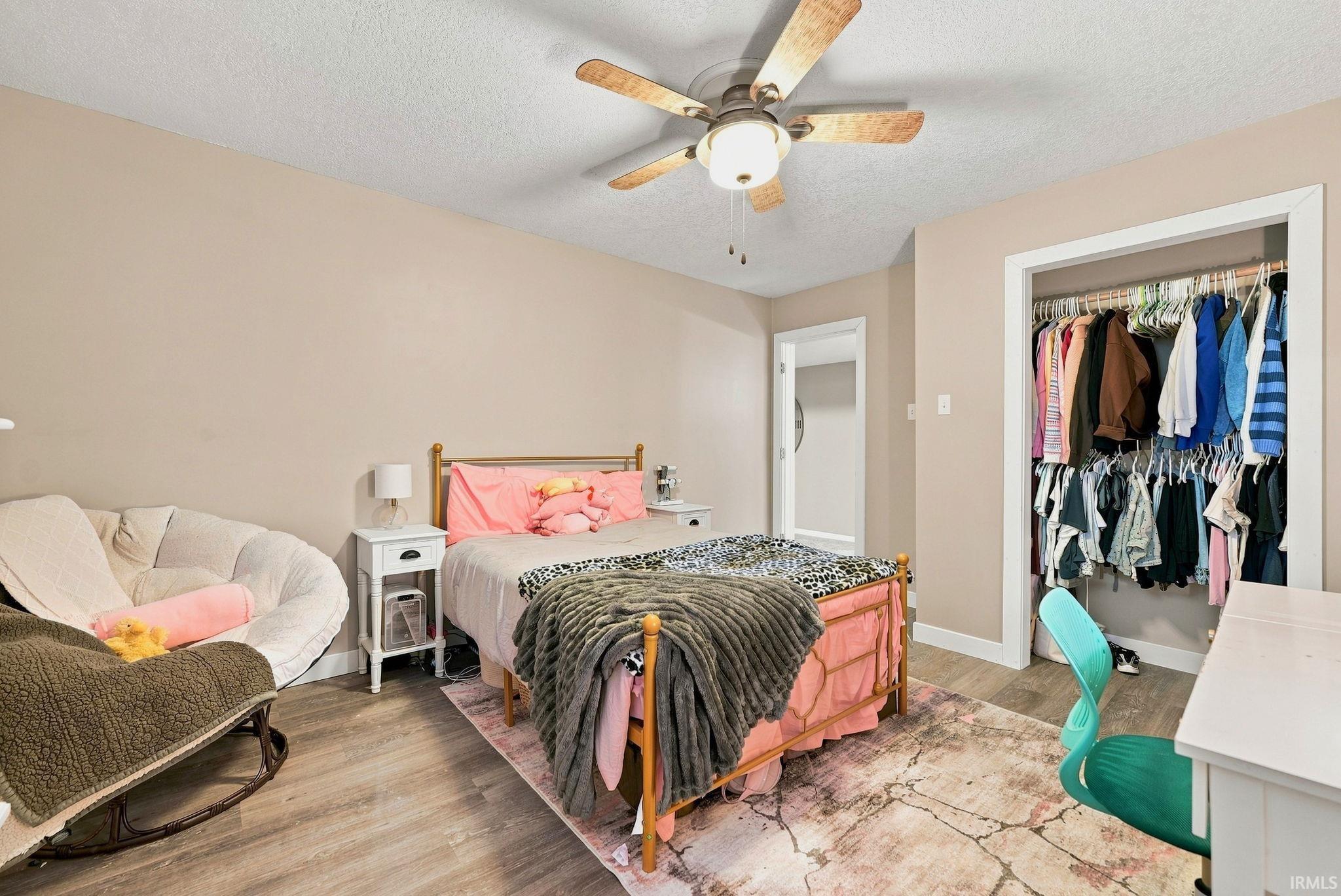 Bedroom featuring wood-finish flooring, a ceiling fan with light, and a built-in closet with hanging rods