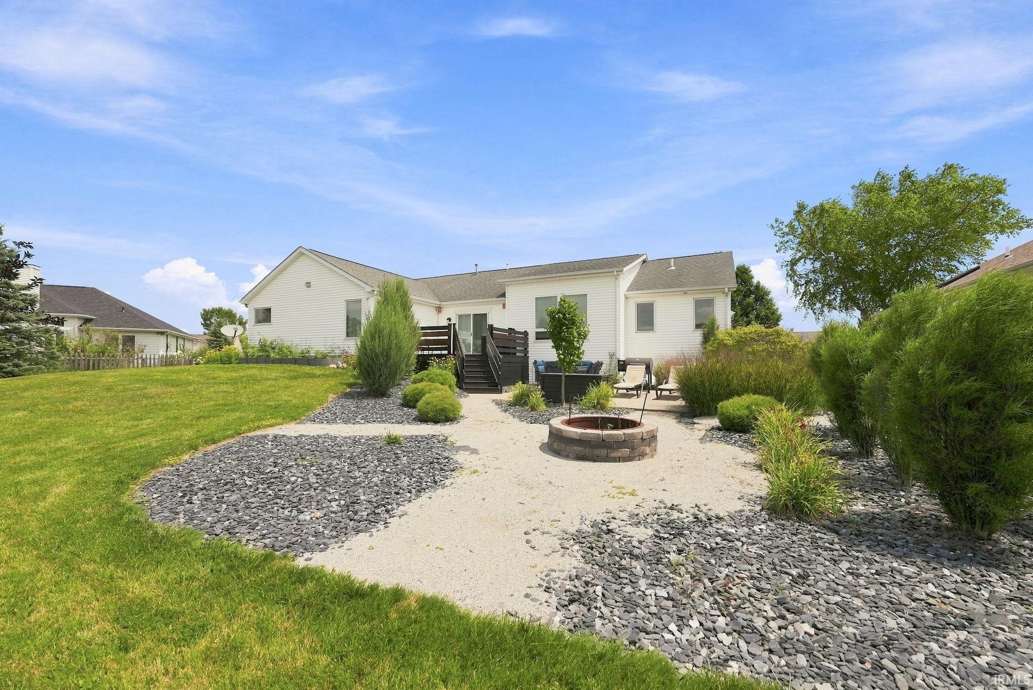 Expansive backyard featuring a stone-lined fire pit, gravel pathways, and decorative rock landscaping