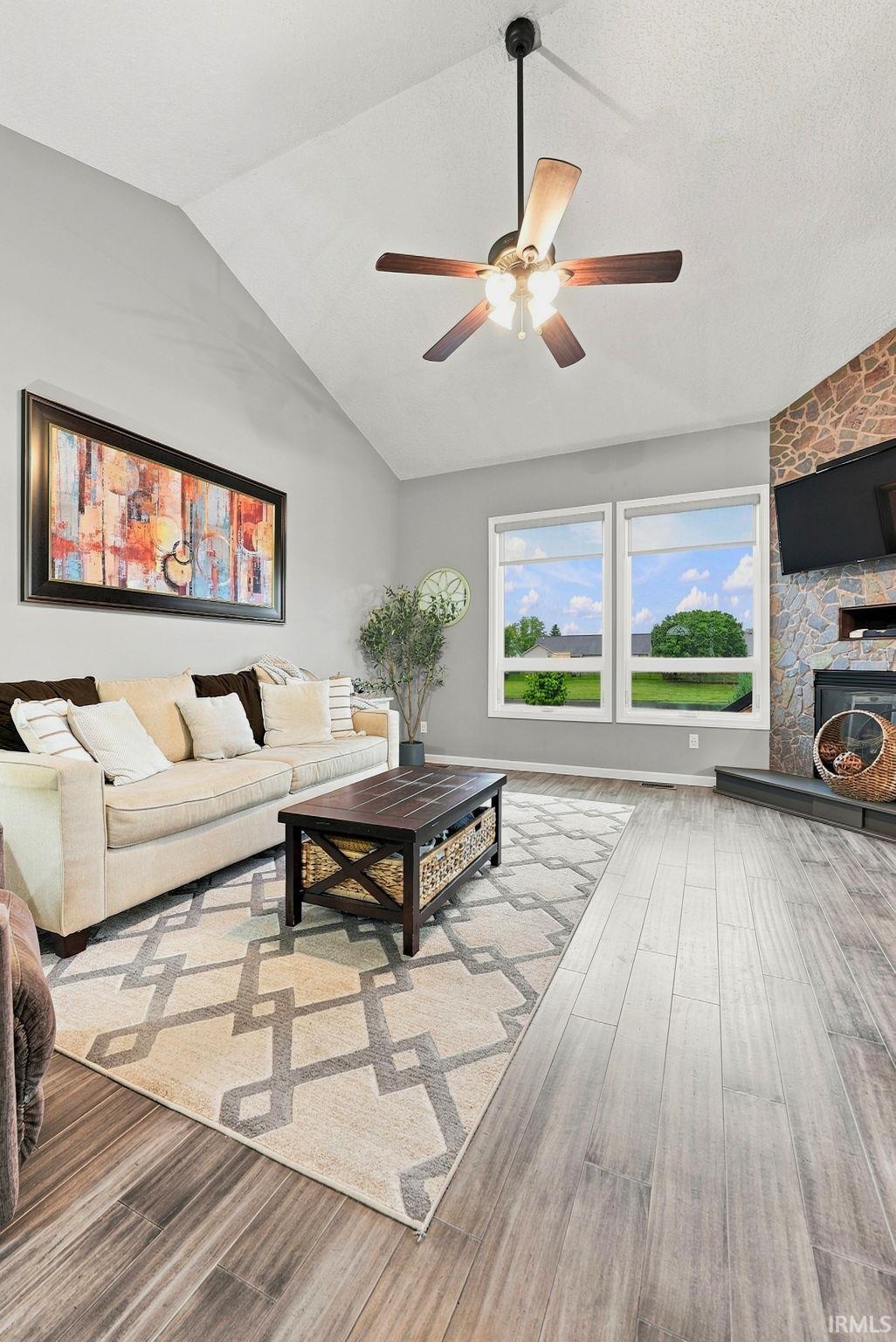 Vaulted ceilings enhance this living space featuring wood-finish flooring and dual windows