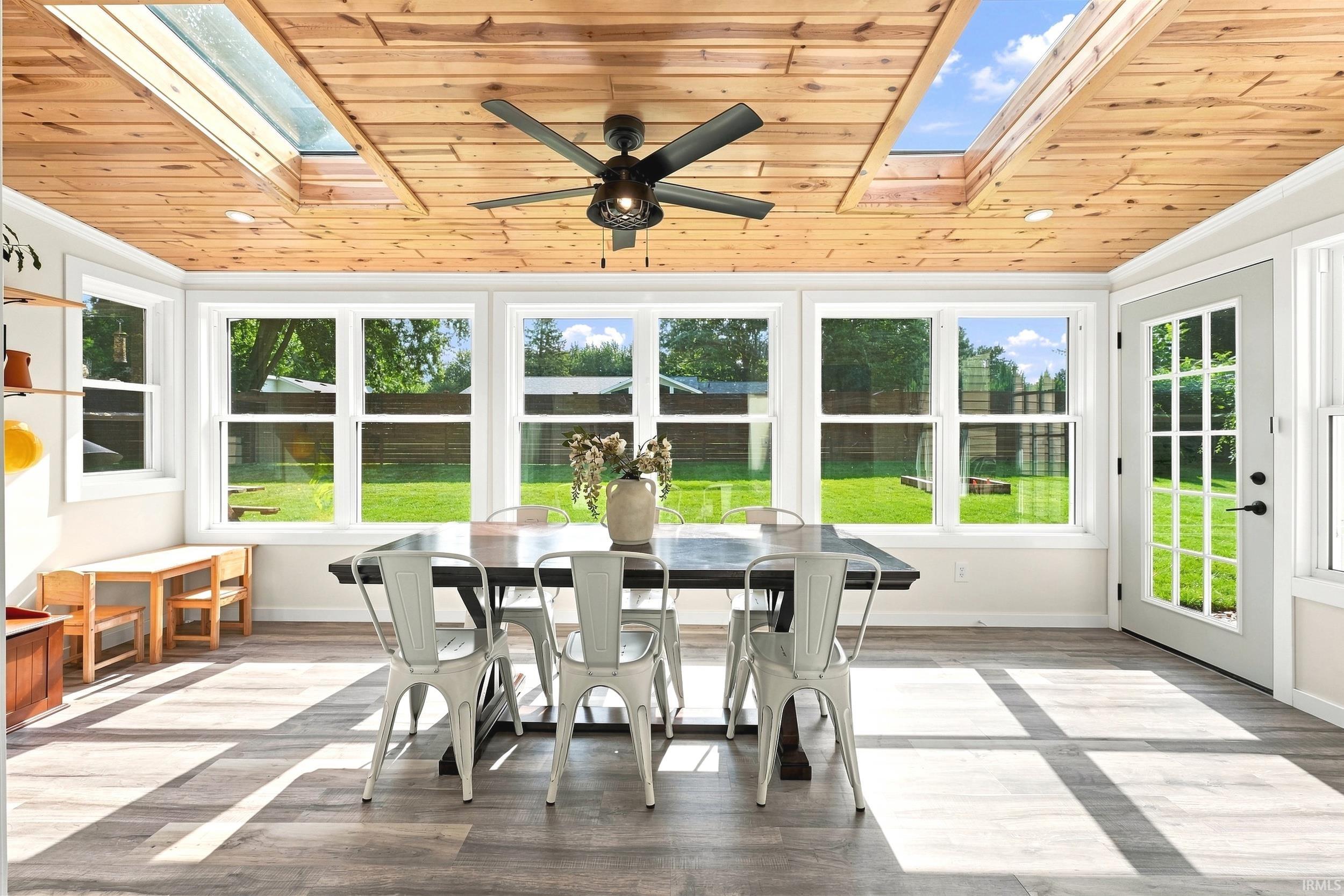 Sunroom featuring a wood-panel ceiling with integrated skylights and a ceiling fan