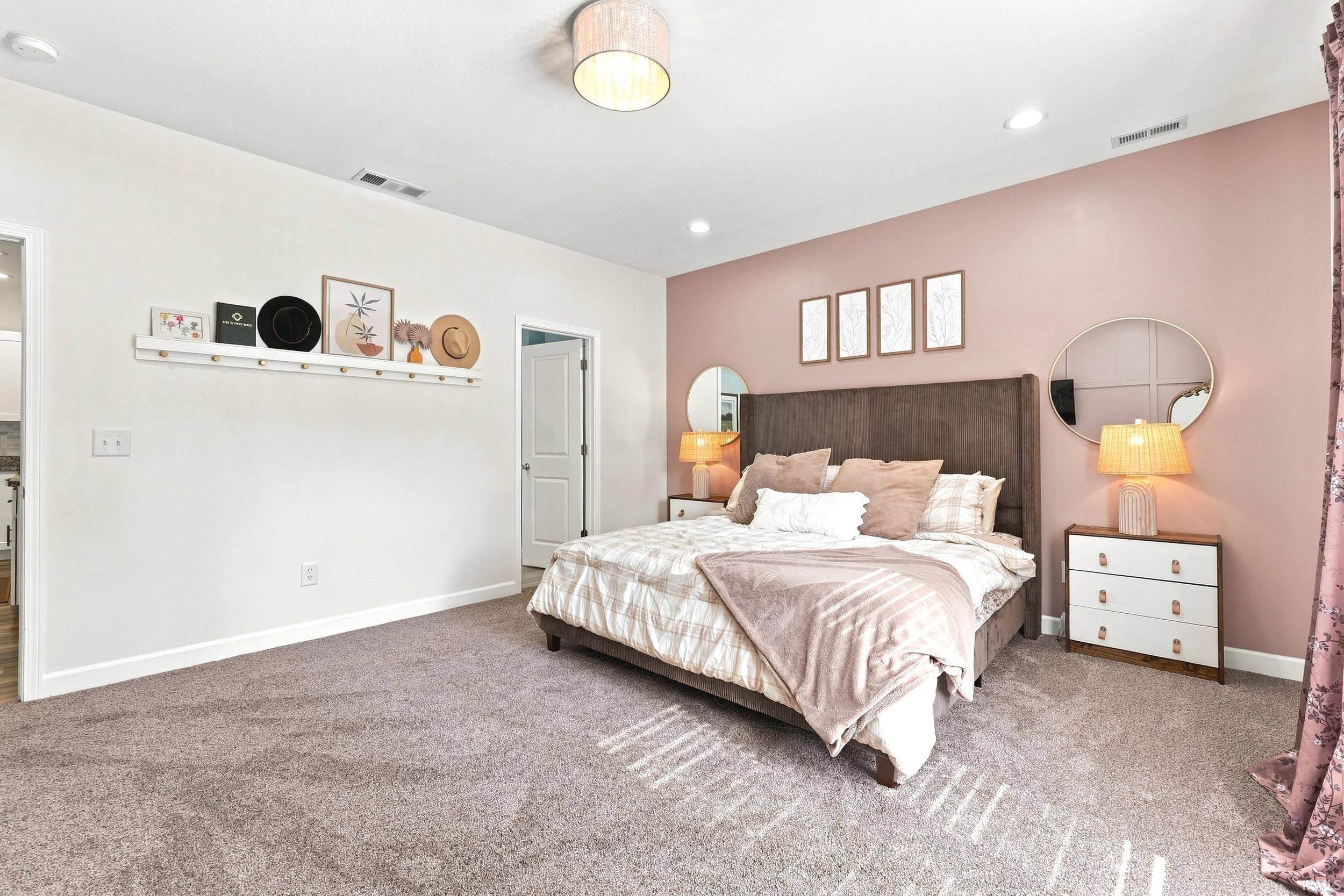 Carpeted bedroom featuring a dark upholstered bed frame, recessed lighting, and a neutral ceiling light fixture