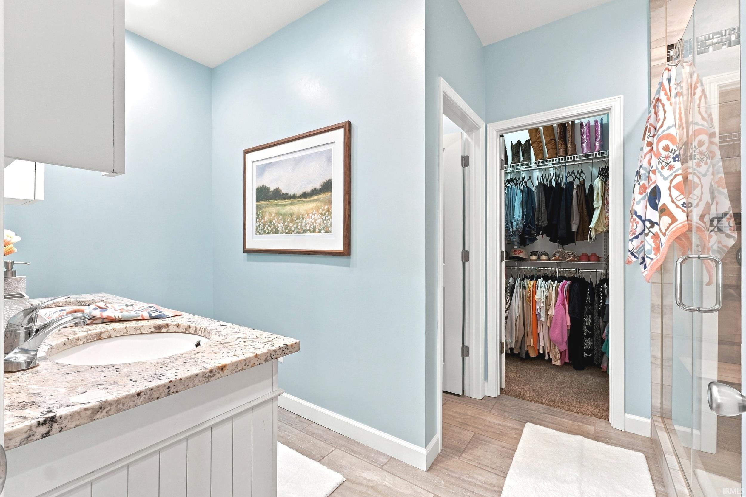 Bathroom vanity featuring a polished granite countertop with an undermount sink and chrome faucet