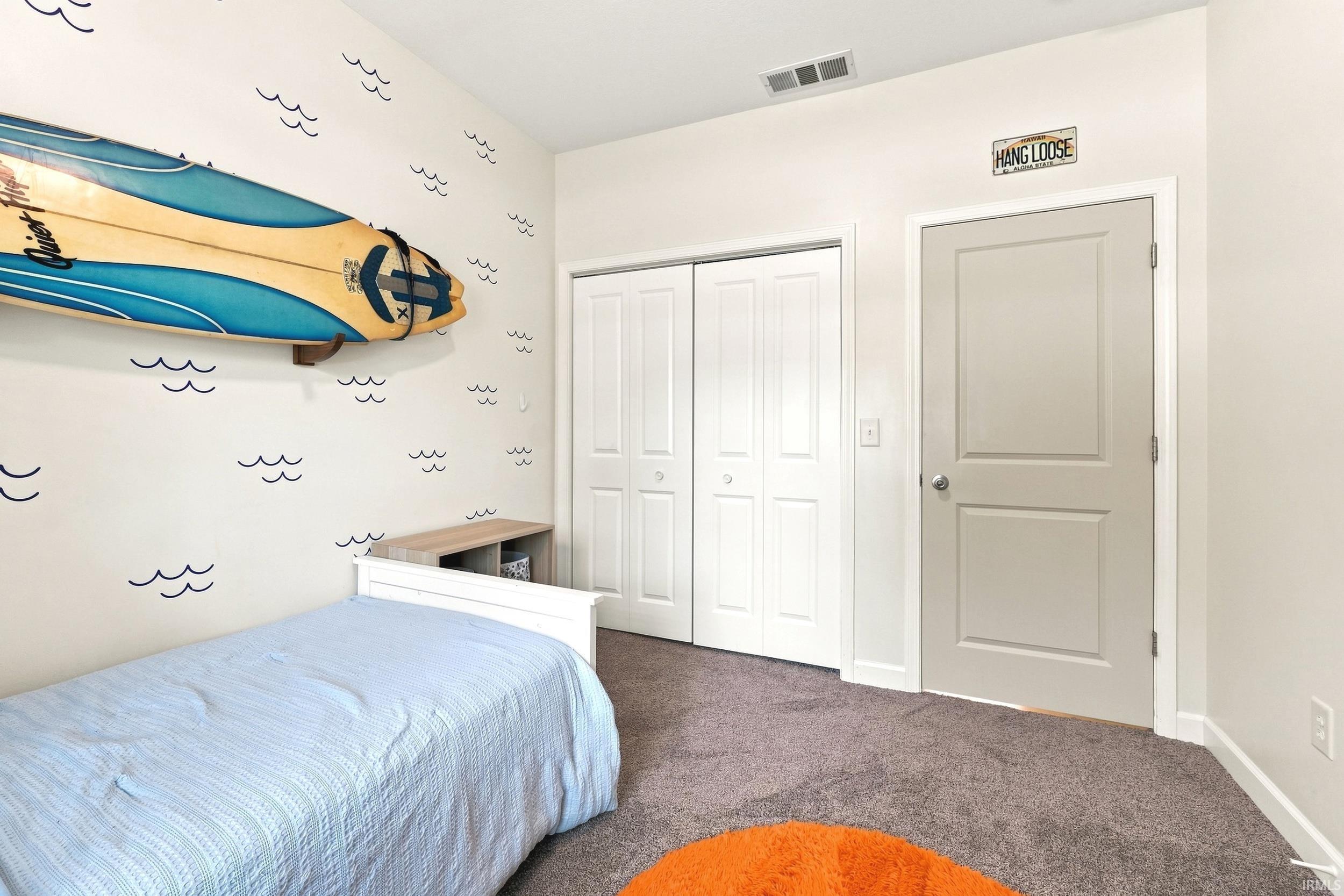 Carpeted room featuring a neutral wall color, white trim, and a white bi-fold closet door