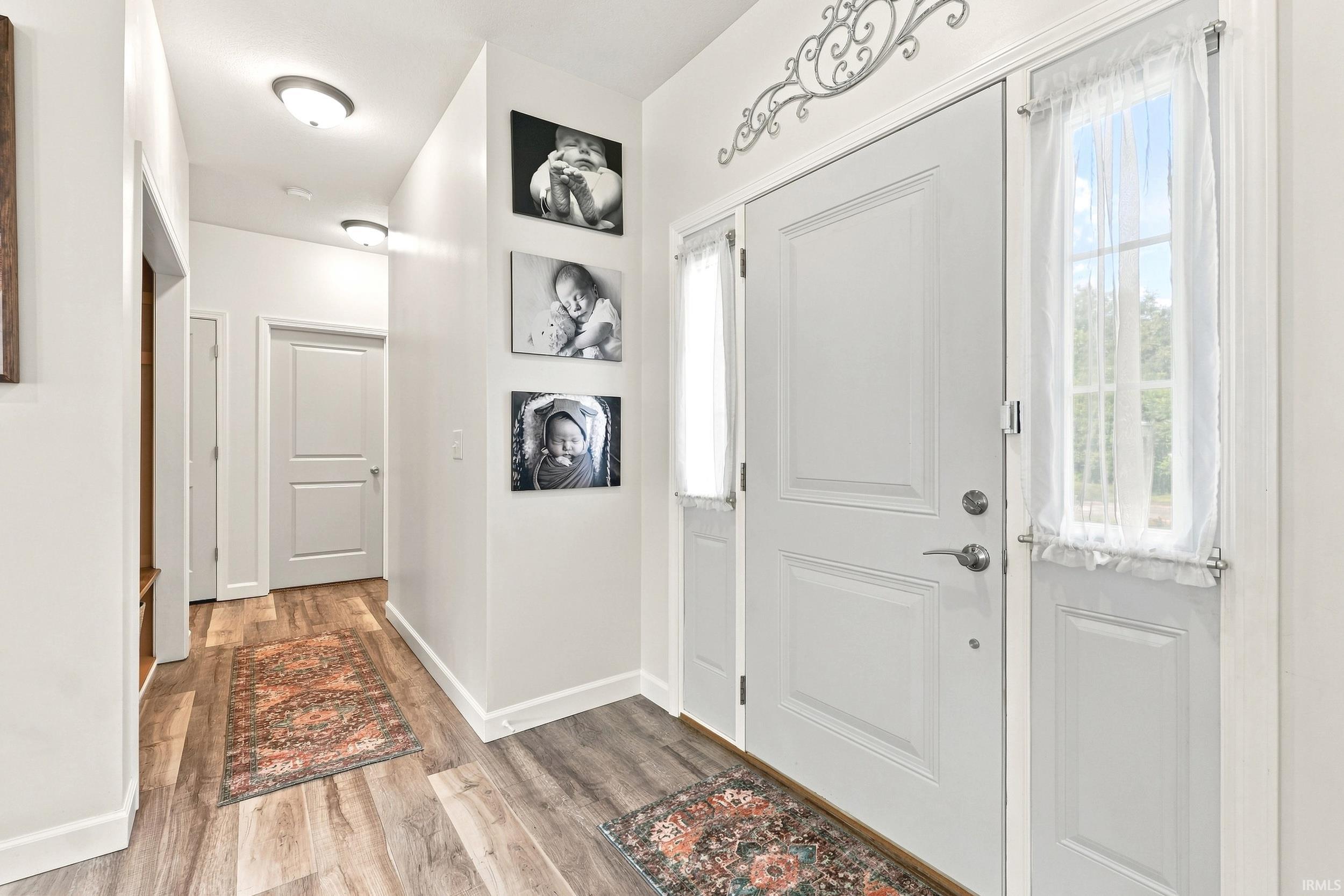 Entryway featuring light wood-finish flooring, white paneled doors, and a decorative transom element