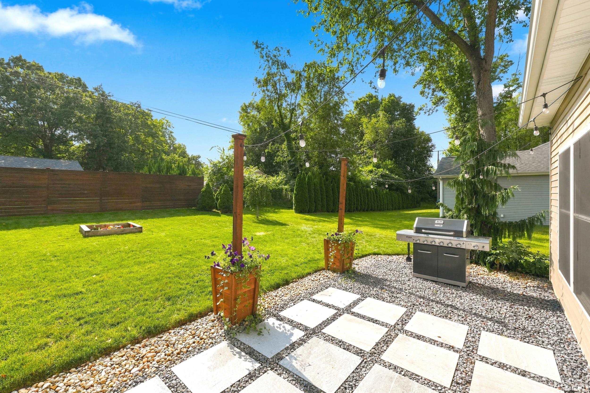Expansive backyard featuring a stone paver patio, gravel accents, and a built-in fire pit