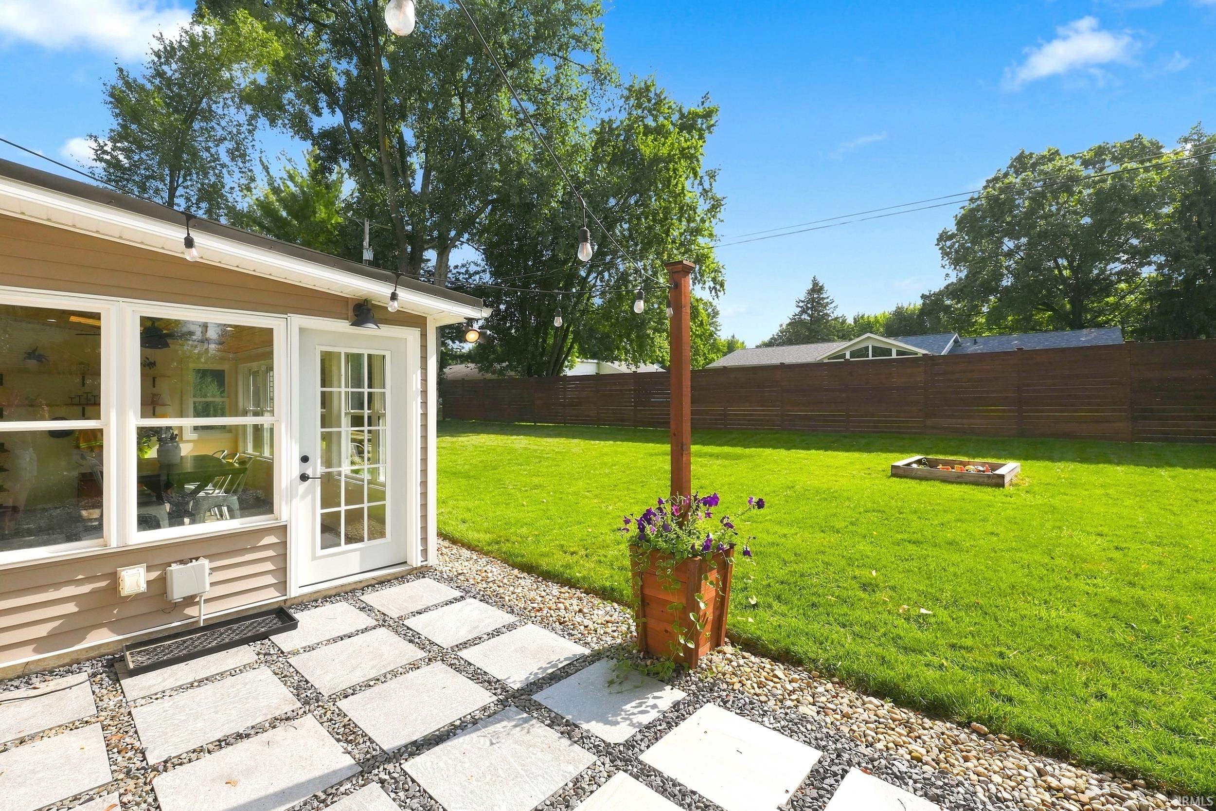 Expansive backyard featuring a manicured lawn, a horizontal wood privacy fence, and a built-in fire pit