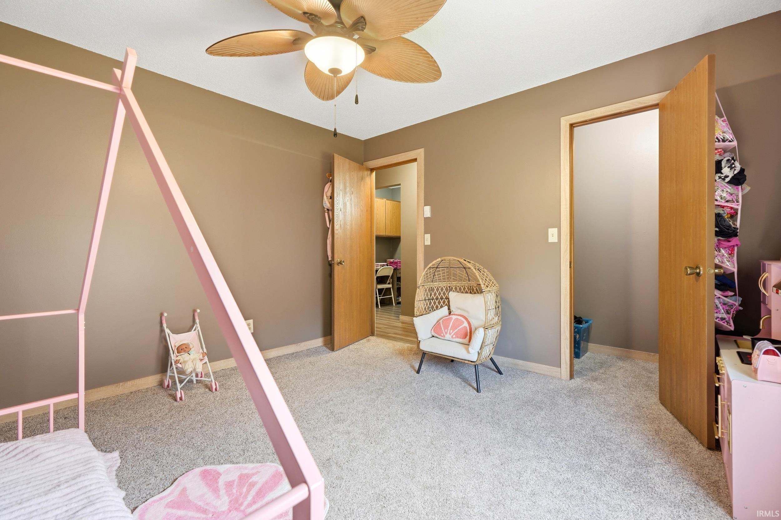 Neutral-toned room featuring a ceiling fan with light fixture, light gray carpeting, and two wooden doors