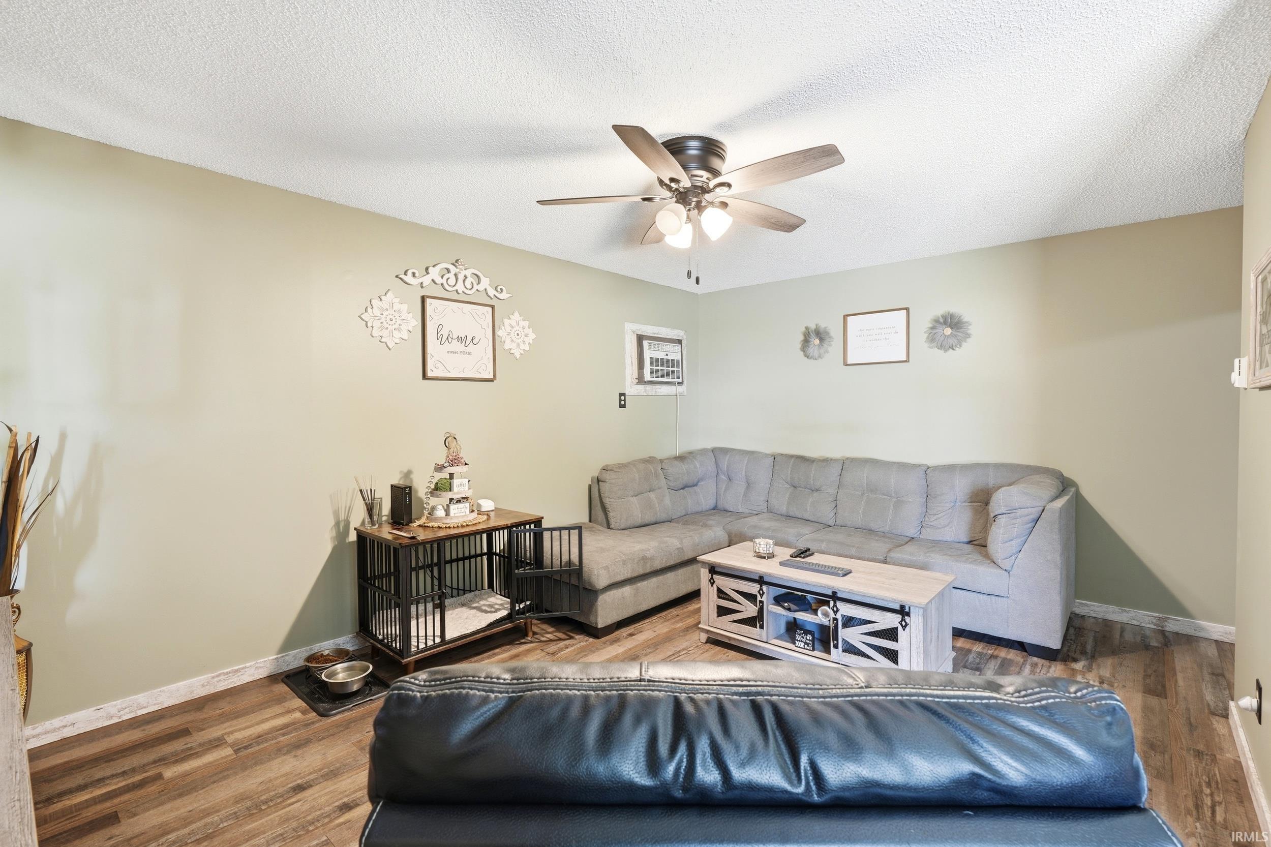 Living area featuring wood-finish flooring, light green walls, and a ceiling fan with integrated lighting
