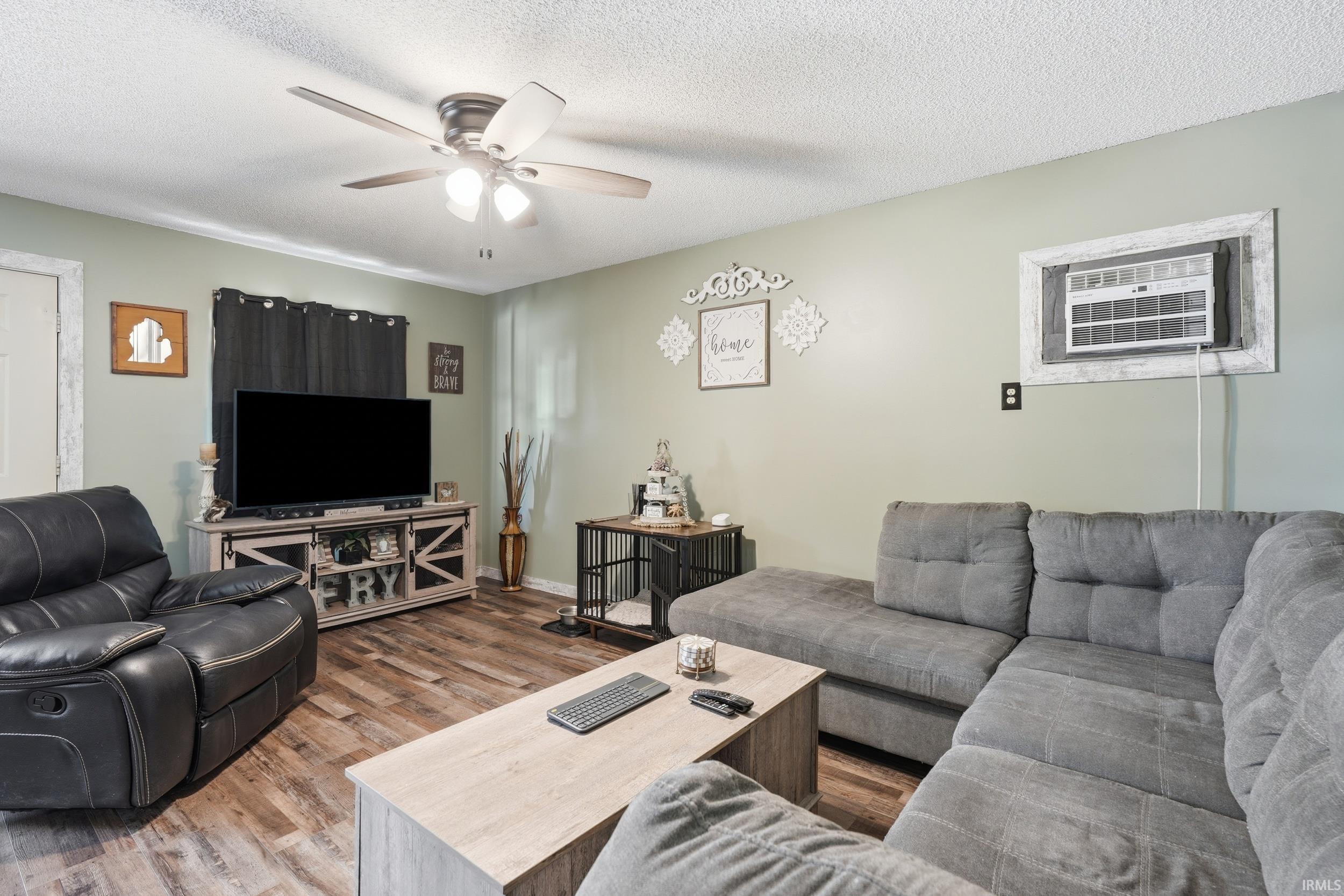 Living area featuring wood-finish flooring and a ceiling fan with integrated lighting