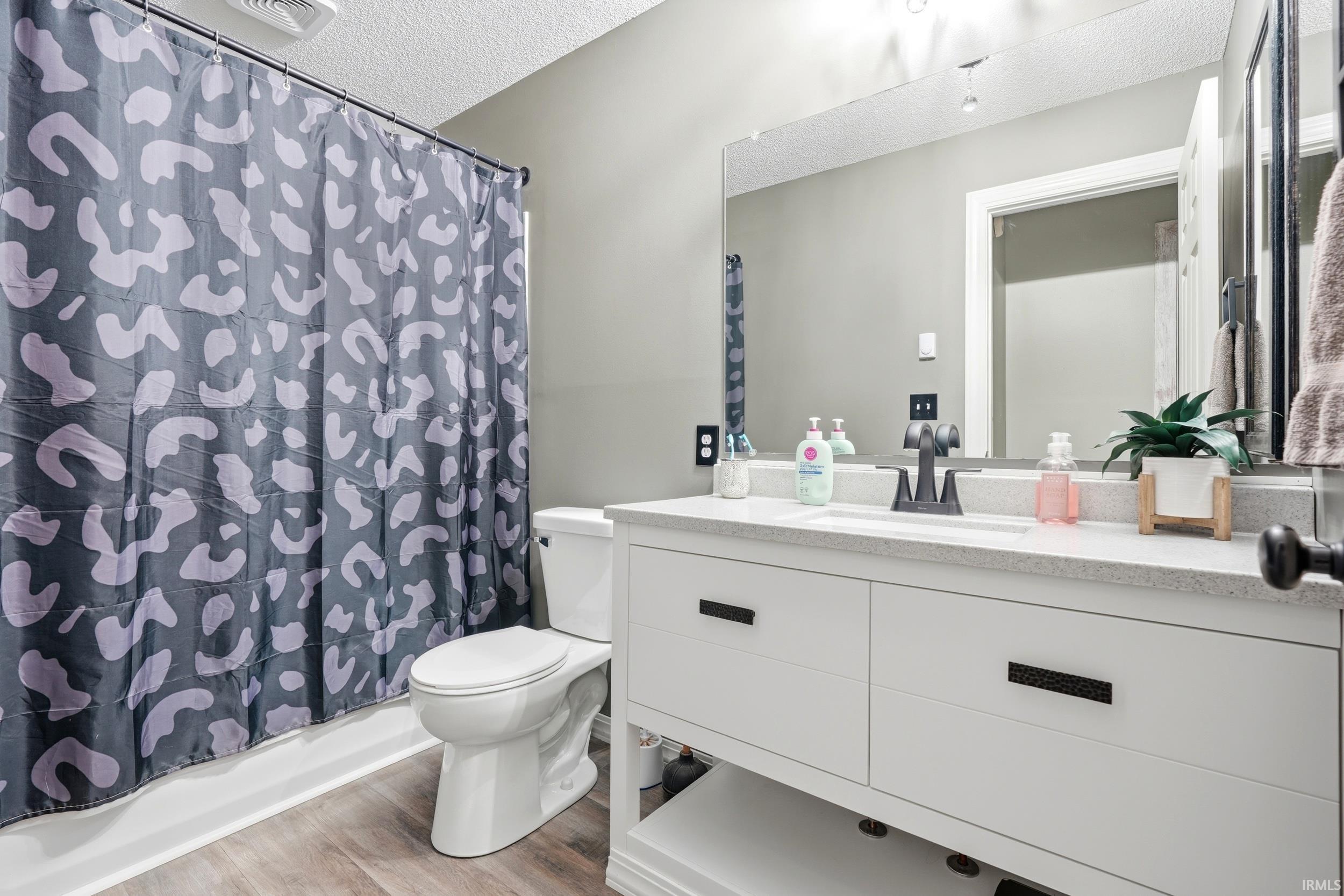 Bathroom featuring a white vanity with black hardware, a recessed sink, and a speckled countertop
