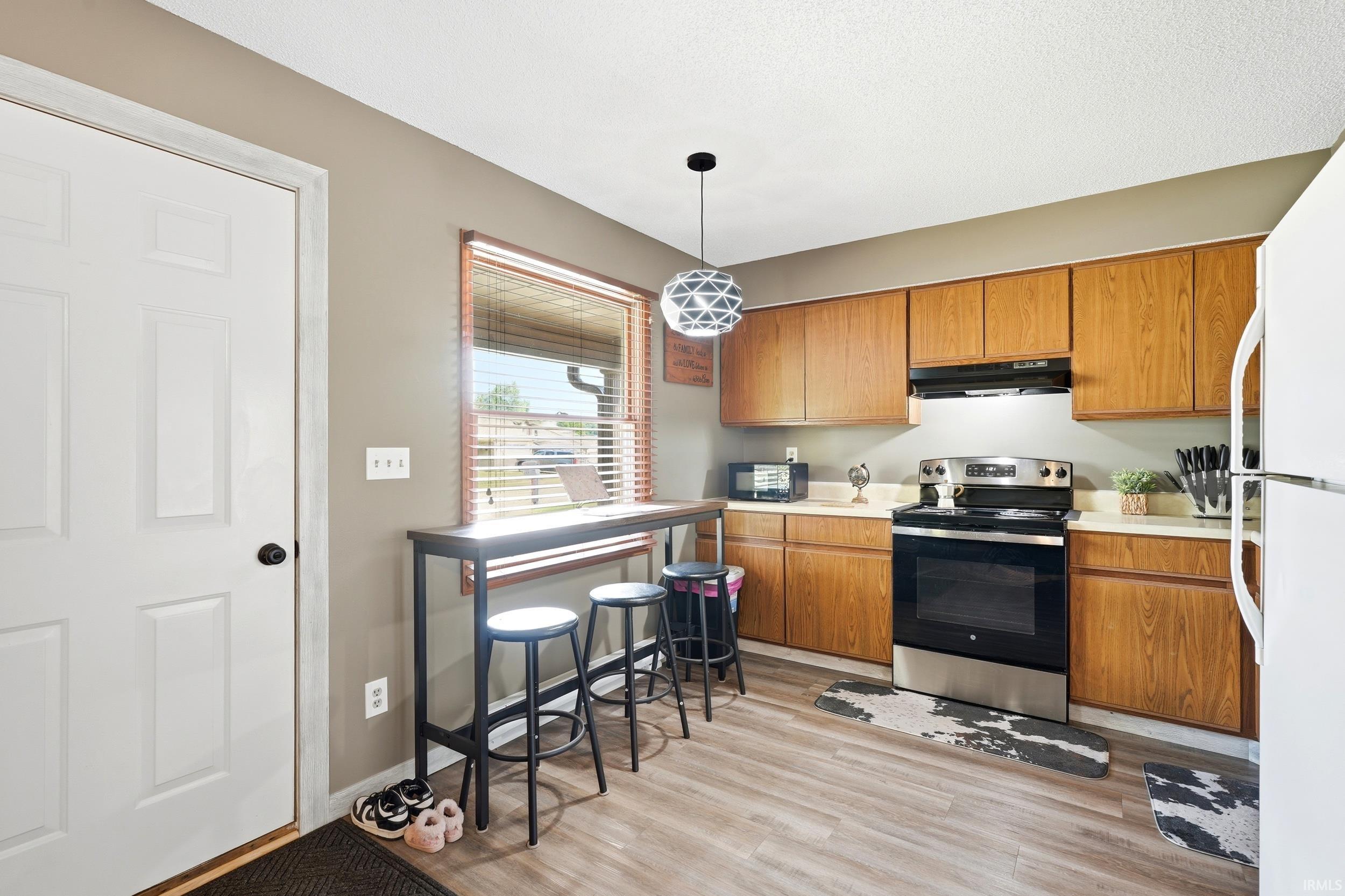 Kitchen featuring wood-finish cabinetry, stainless steel range, and light-toned countertops