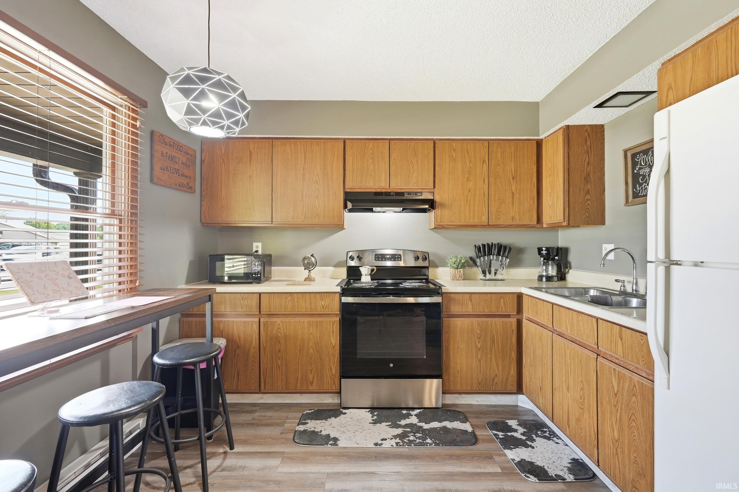 Efficient kitchen featuring wood-finish cabinetry, light-toned countertops, and wood-finish flooring