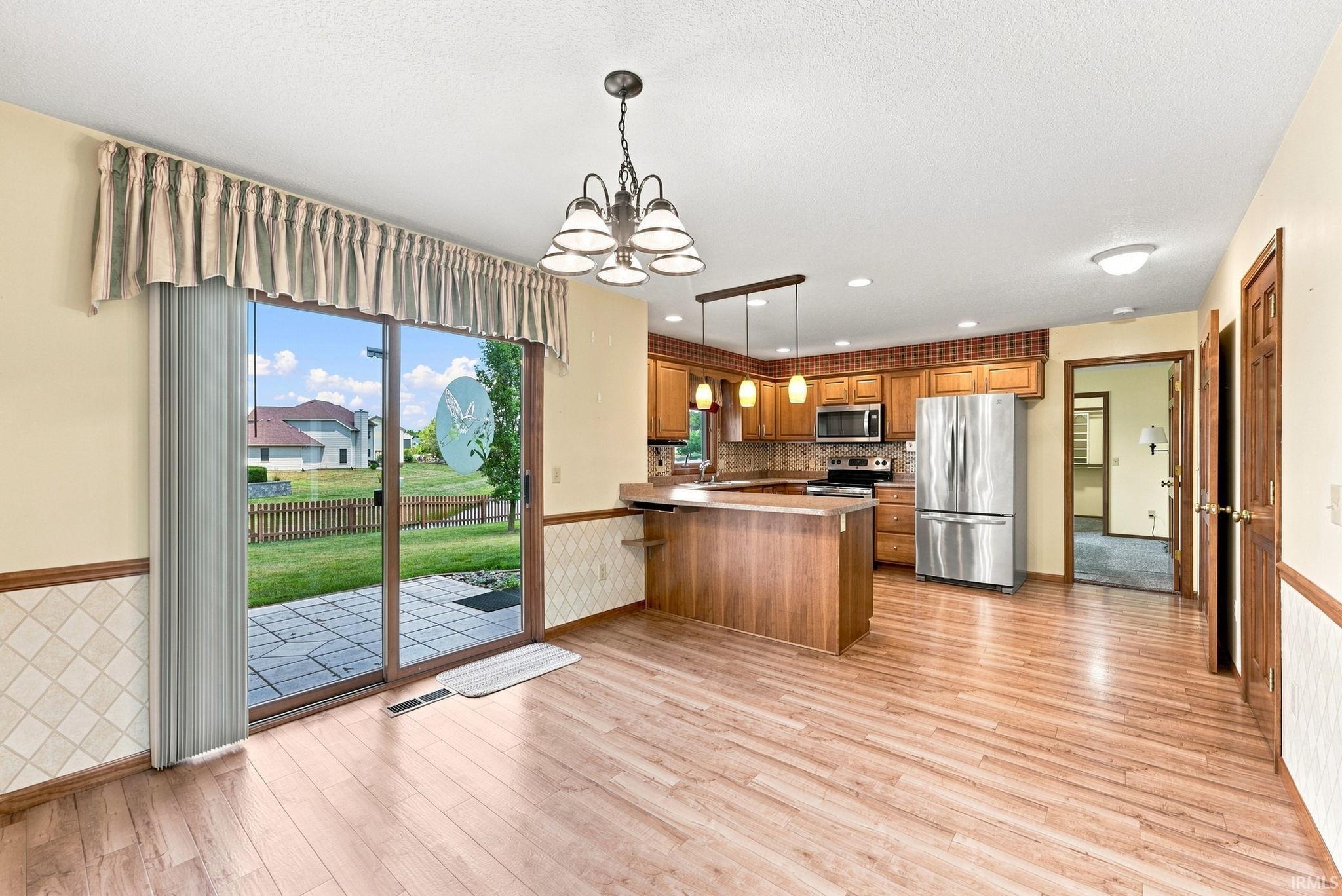Open-concept kitchen and dining area featuring wood-finish flooring, a breakfast bar, and stainless steel appliances