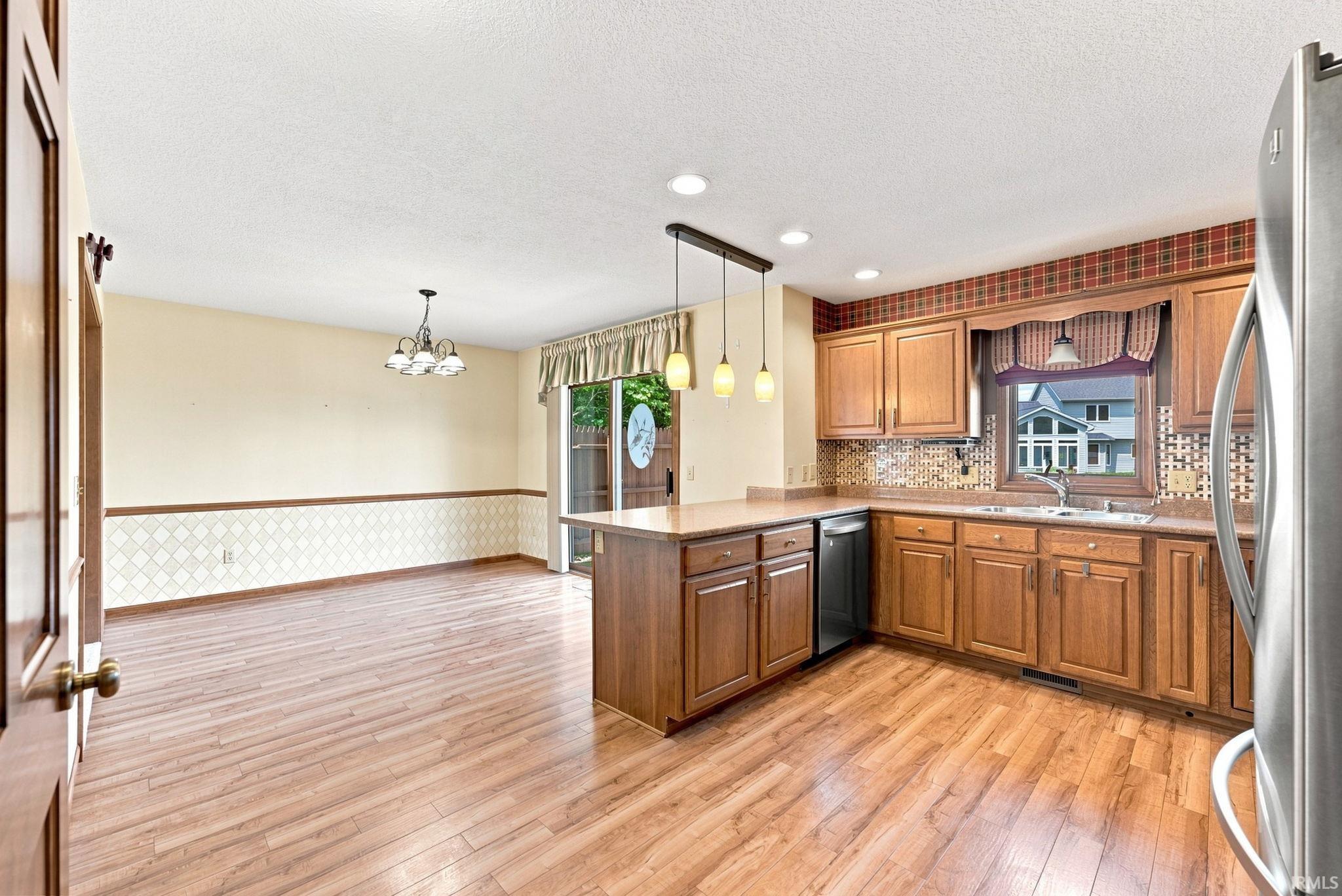 Open-concept kitchen and dining area featuring wood-finish flooring, recessed lighting, and a kitchen island with pendant lighting