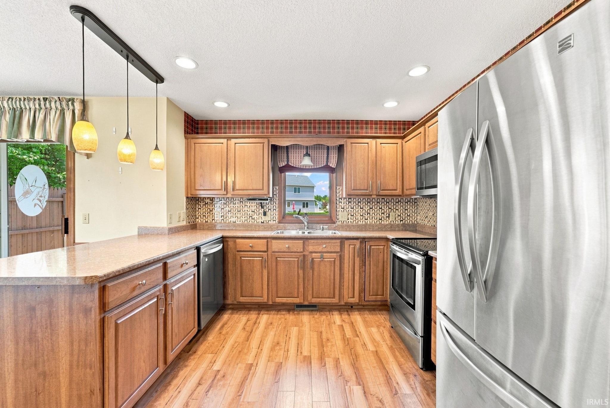 Well-appointed kitchen featuring wood-finish cabinetry, light-toned countertops, and a mosaic tile backsplash