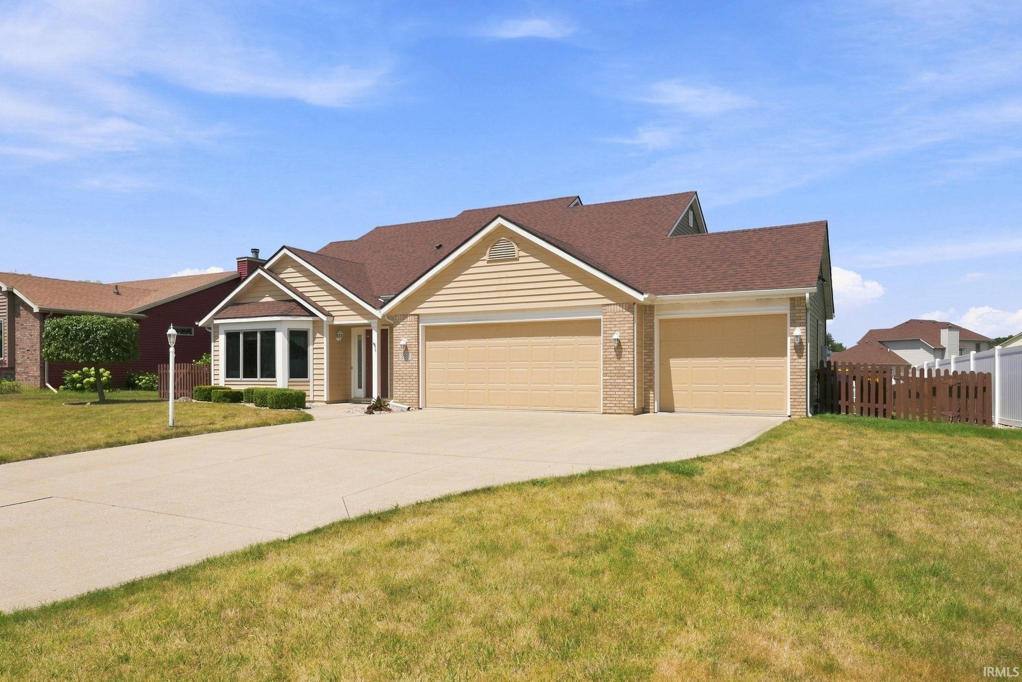 Traditional-style residence featuring a two-car garage with tan doors, light brick detailing, and horizontal siding