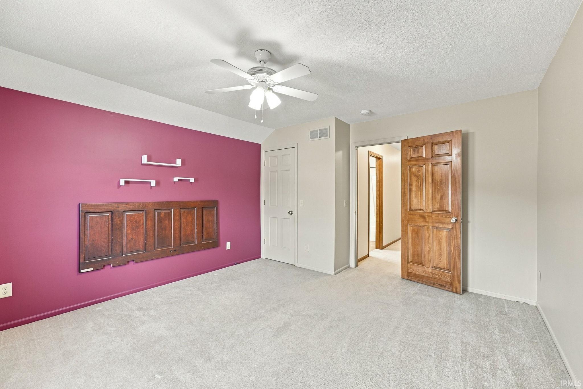 Carpeted room featuring a ceiling fan, paneled wood door, and a closet with a bi-fold door