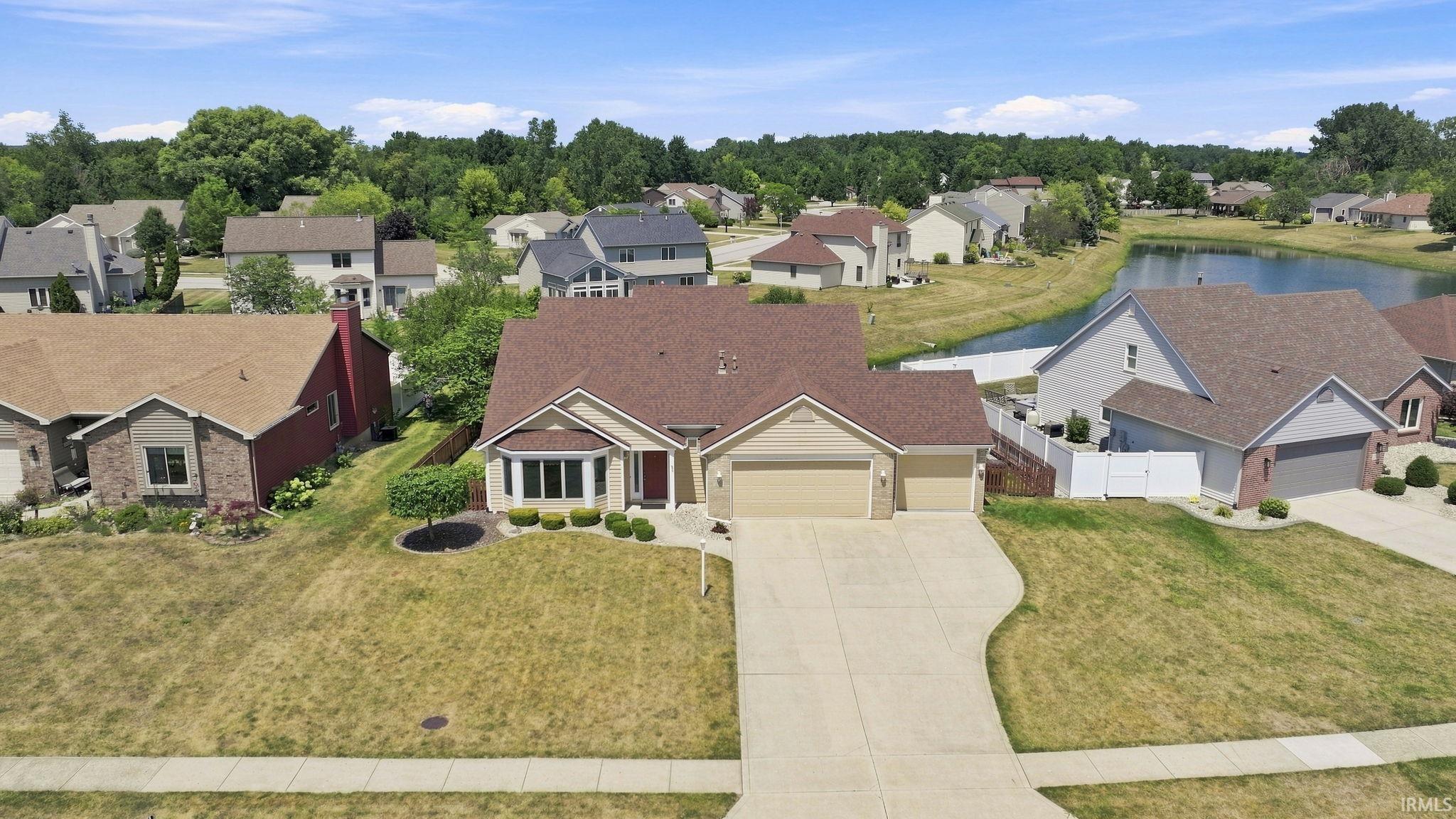 Charming ranch-style residence featuring a cream-colored exterior, two-car attached garage, and expansive manicured lawn