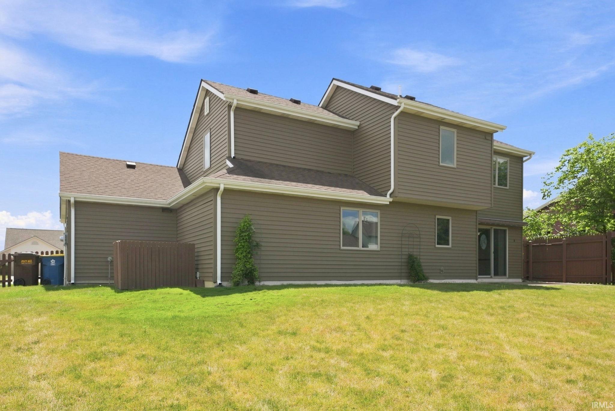 Spacious backyard featuring a manicured lawn, full privacy fencing, and direct access to the interior via a patio door