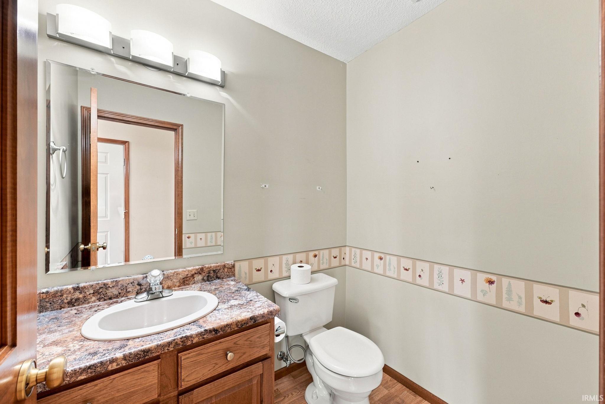Bathroom featuring a wood-finish vanity with an integrated sink and a stone-look countertop, complemented by a rectangular wall-mounted mirror
