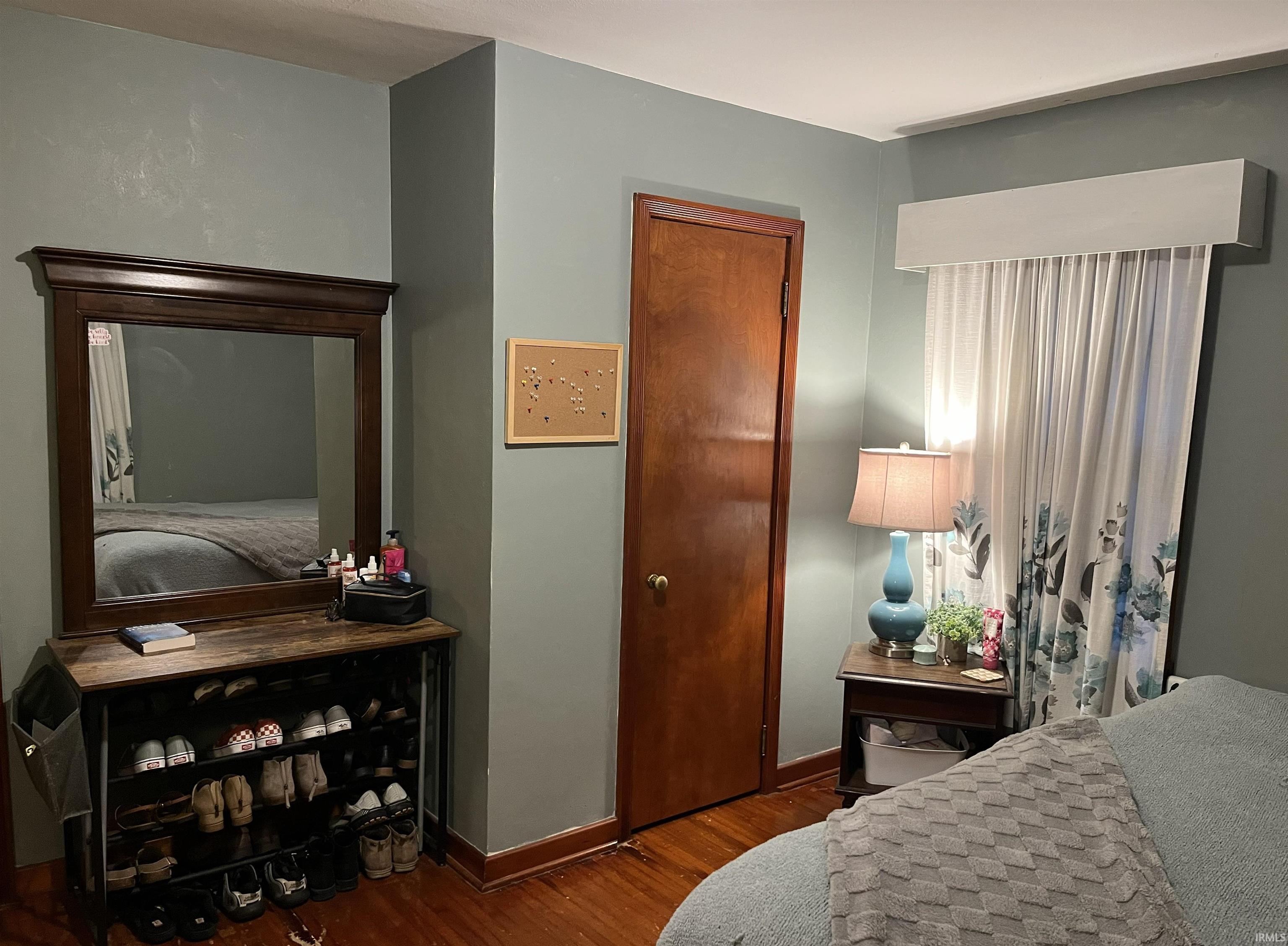 Hardwood flooring throughout, featuring a natural wood door, and light blue-grey wall paint