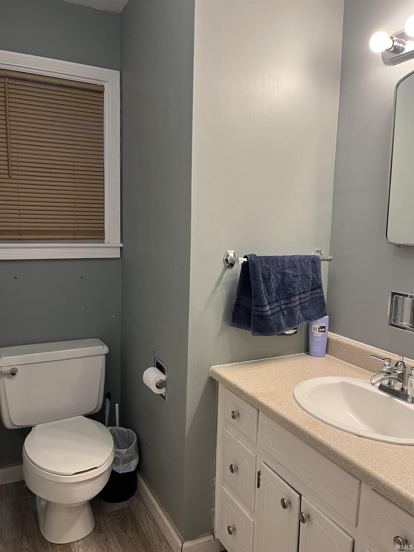 Bathroom featuring a white vanity with cabinet storage, a built-in sink, and a light-colored countertop