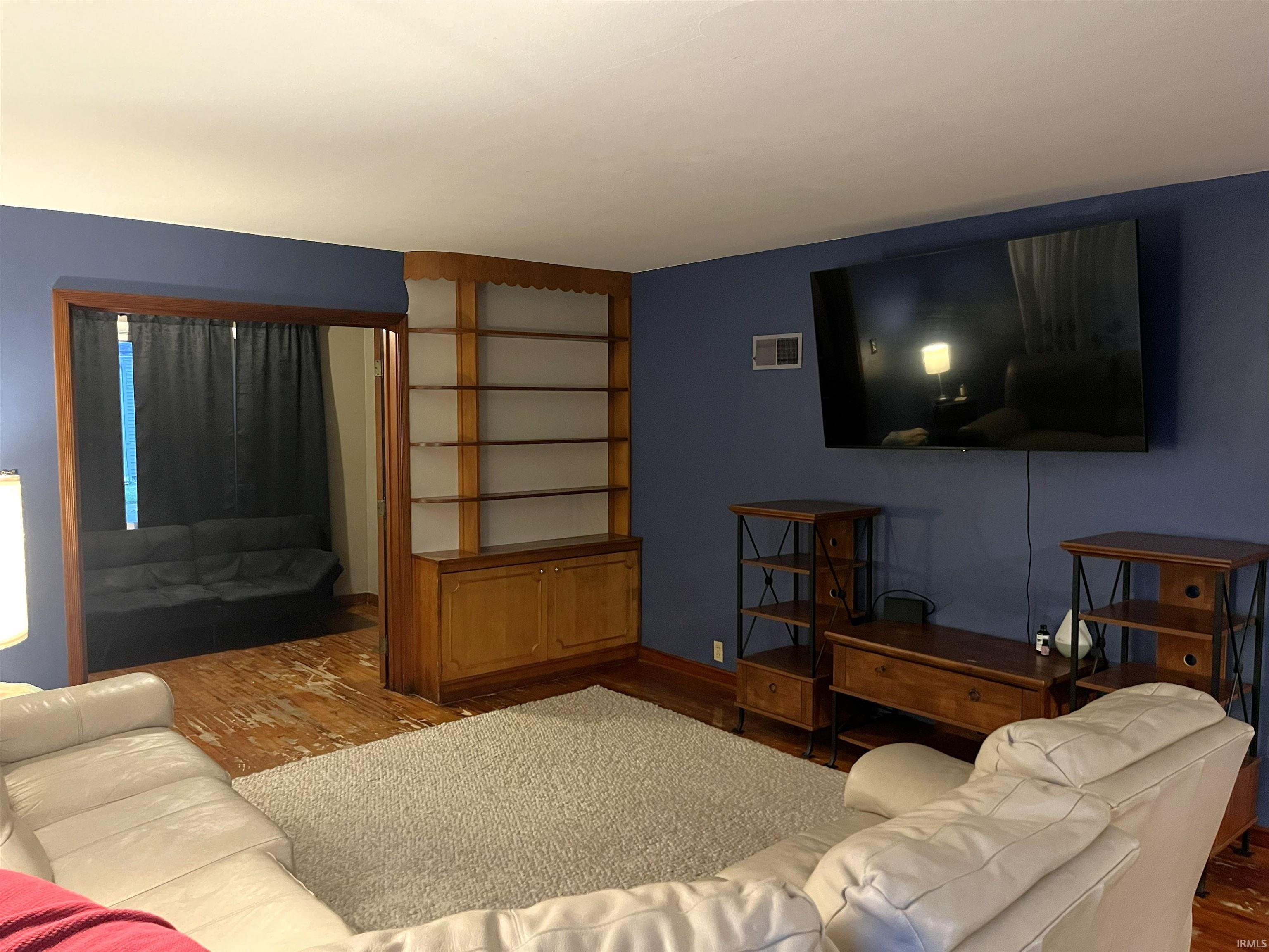 Living area with wood-finish flooring and a built-in wooden bookcase with lower cabinetry