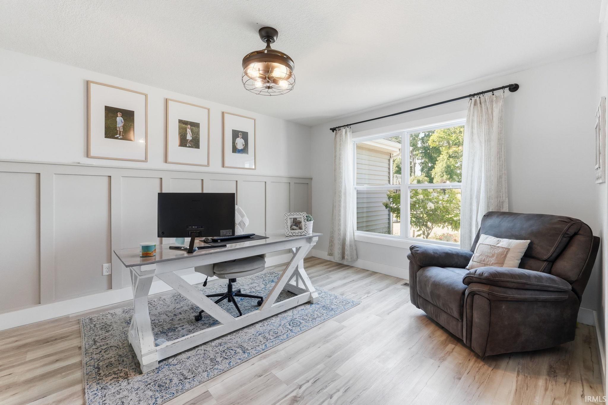 Room featuring board and batten detailing, wood-finish flooring, and a ceiling fan with integrated lighting