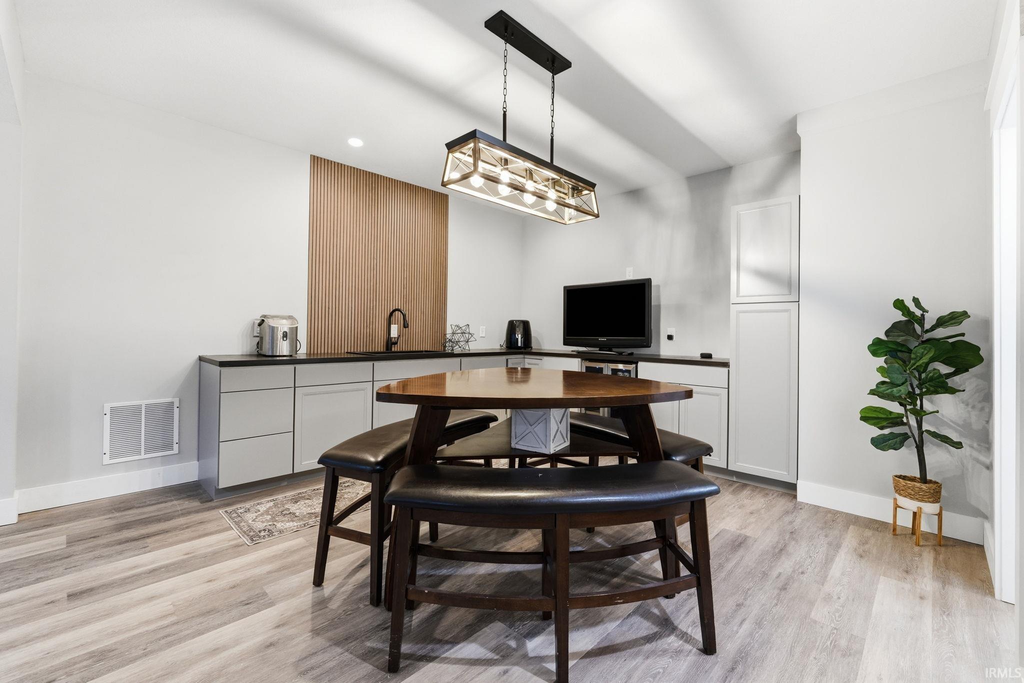 Wet bar featuring a black countertop, modern cabinetry, and a wood-slat accent wall