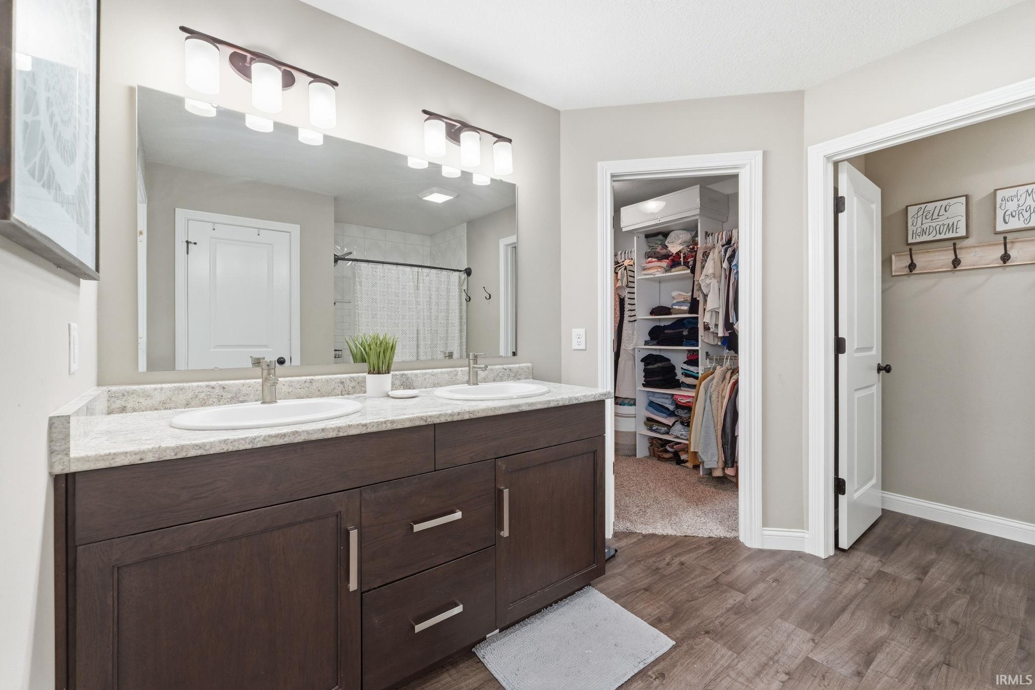 Bathroom featuring a dark wood-finish double vanity with white oval sinks and a light speckled countertop
