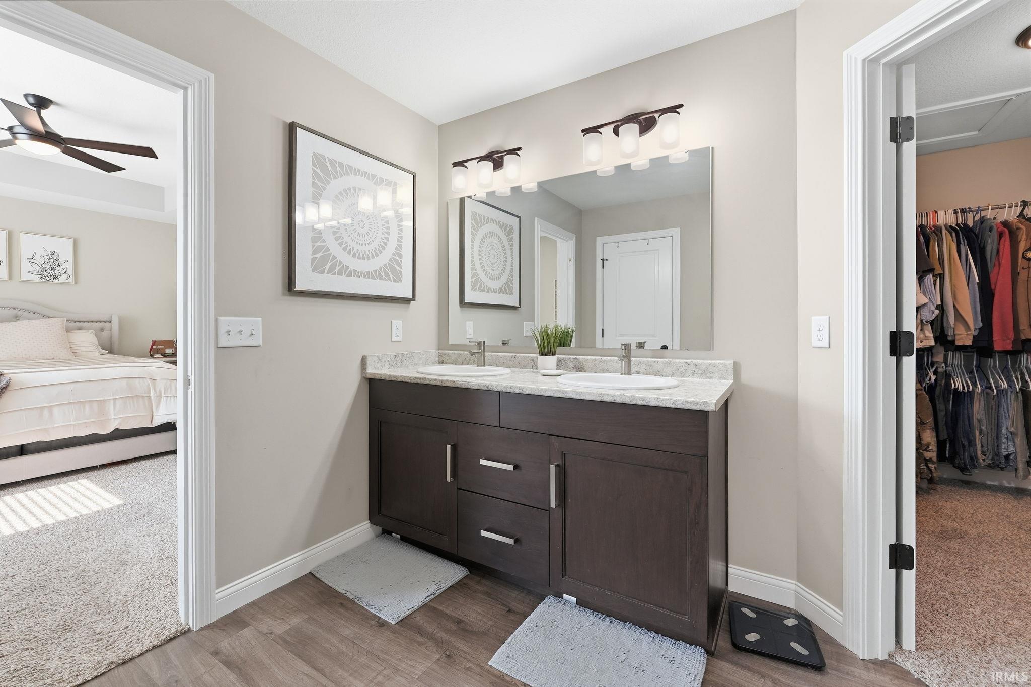 Double vanity featuring a light-colored countertop, dual sinks, and wood-finish flooring