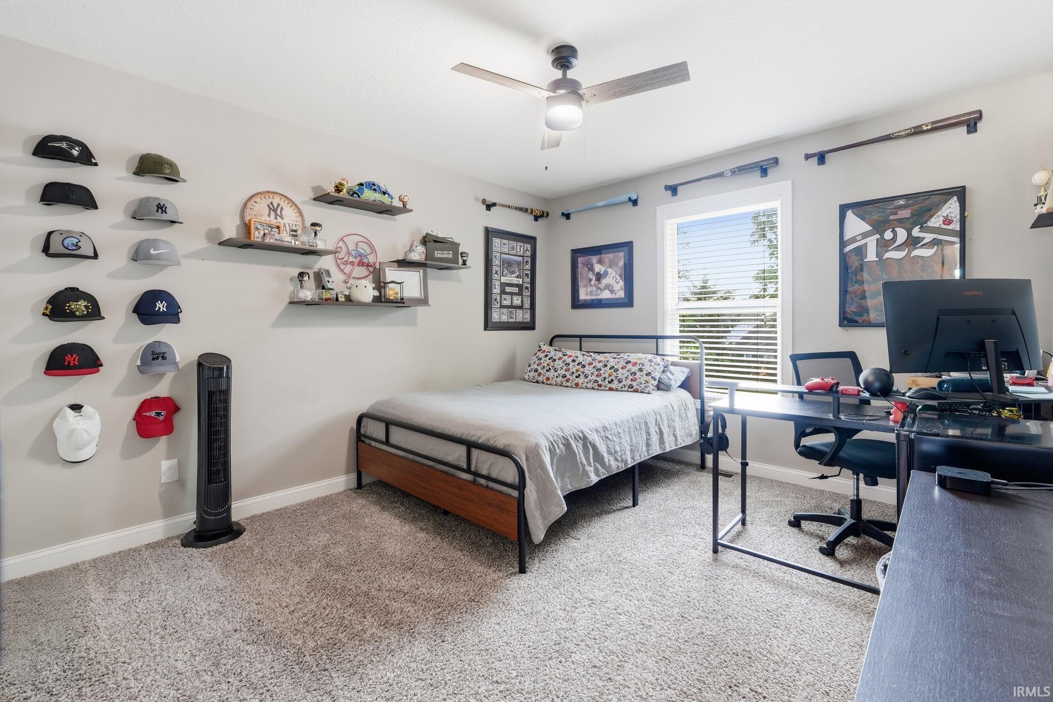 Carpeted room featuring a ceiling fan with light, a window with horizontal blinds, and a built-in wall shelf