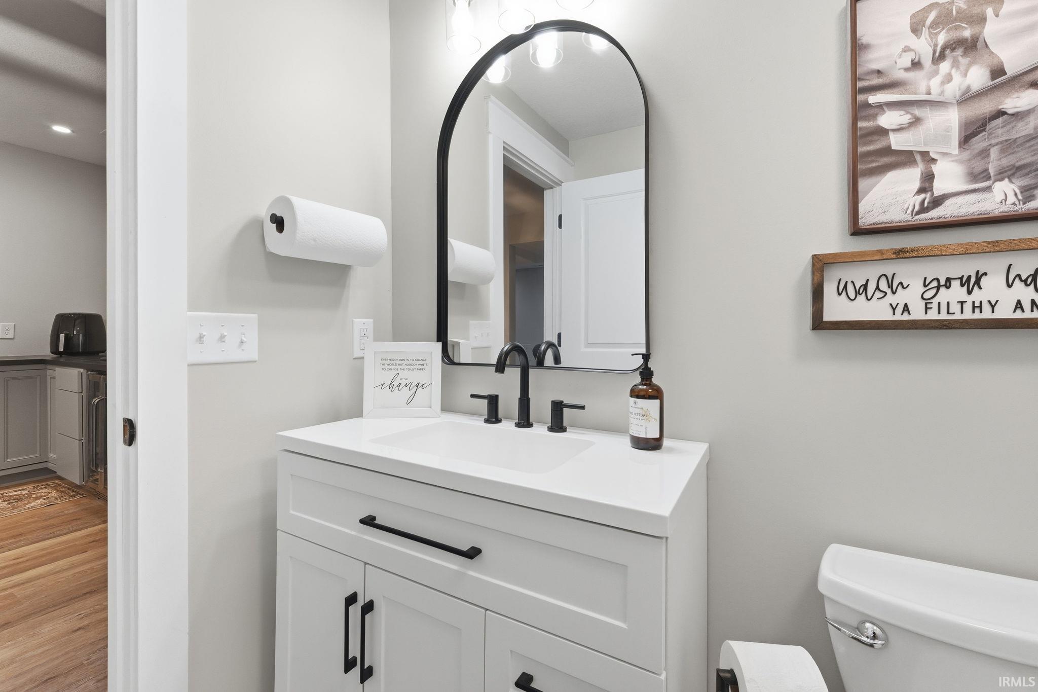 Bathroom featuring a white vanity with integrated sink, black fixtures, and an arched black-framed mirror