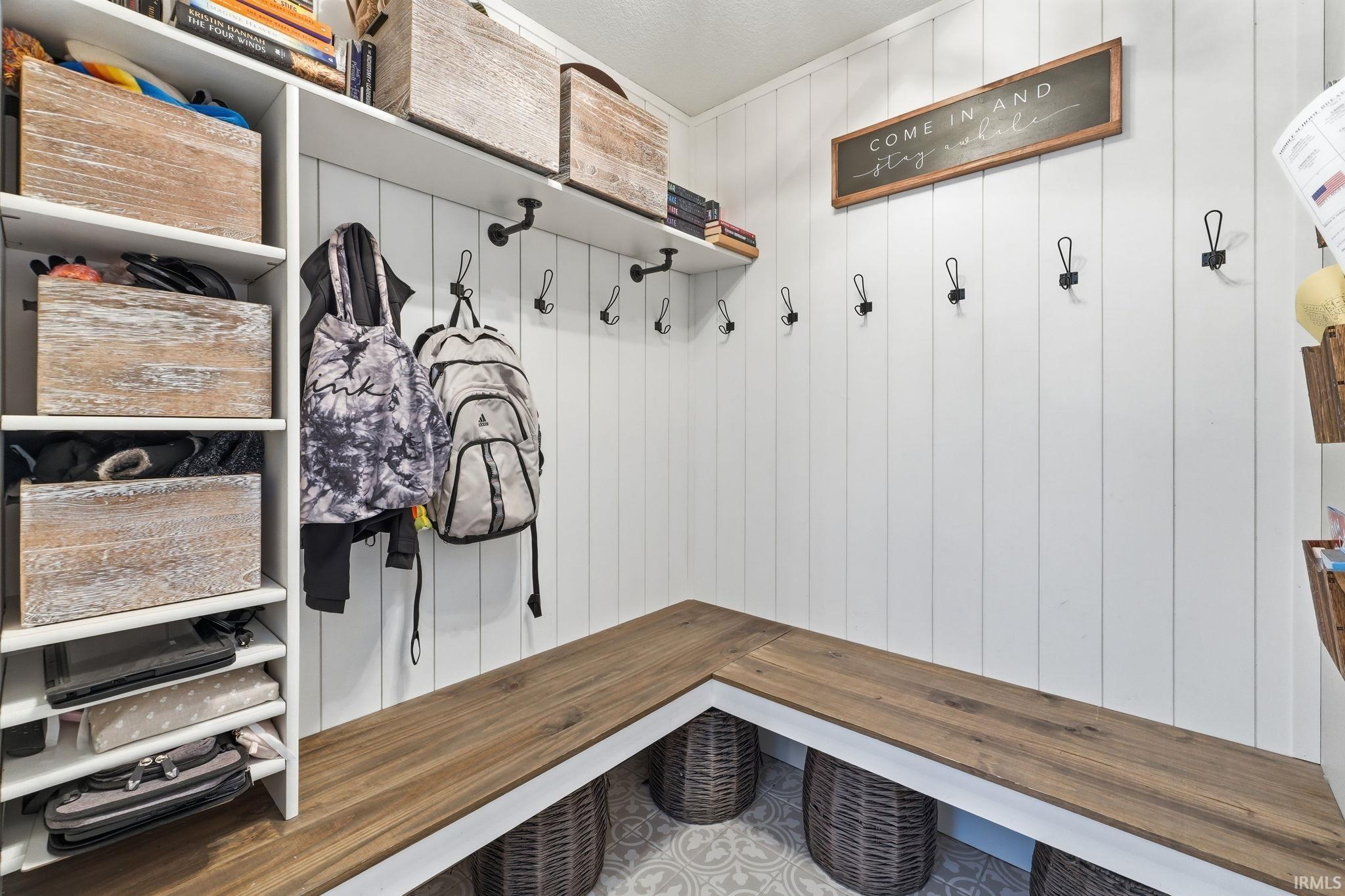 Built-in entryway storage featuring a wood-finish bench, vertical plank wall paneling, and integrated open shelving