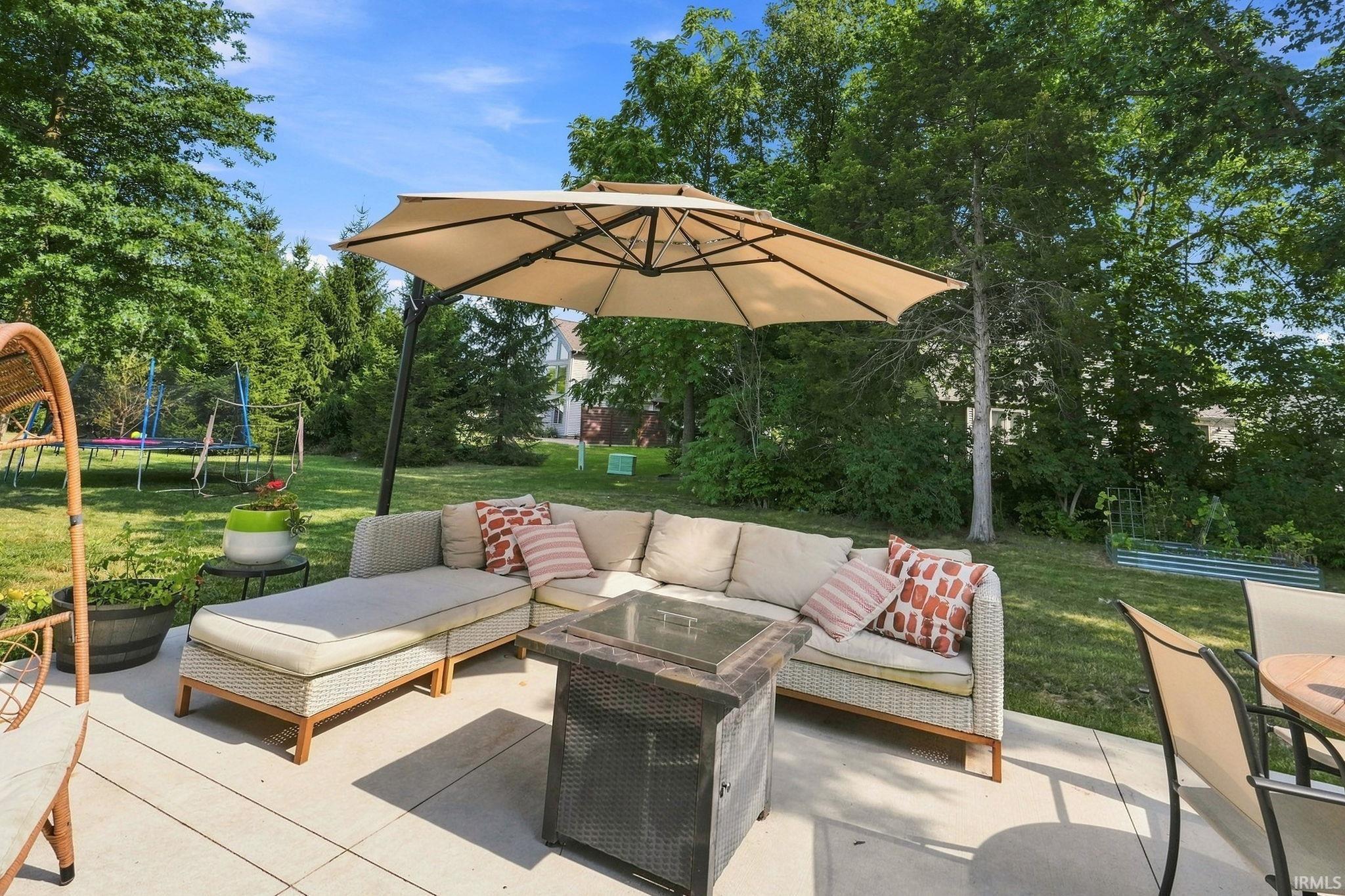 Expansive patio featuring light-colored paving stones, a built-in fire pit, and ample space for outdoor furnishings