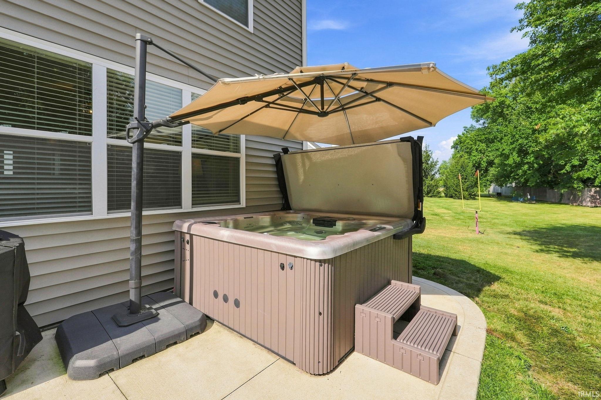 Outdoor hot tub featuring a two-step entry, situated on a concrete patio