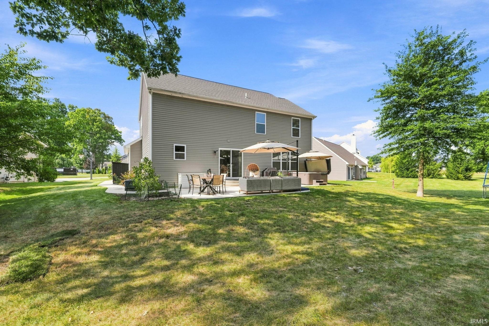 Expansive exterior featuring a concrete patio, sliding glass doors, and light gray siding