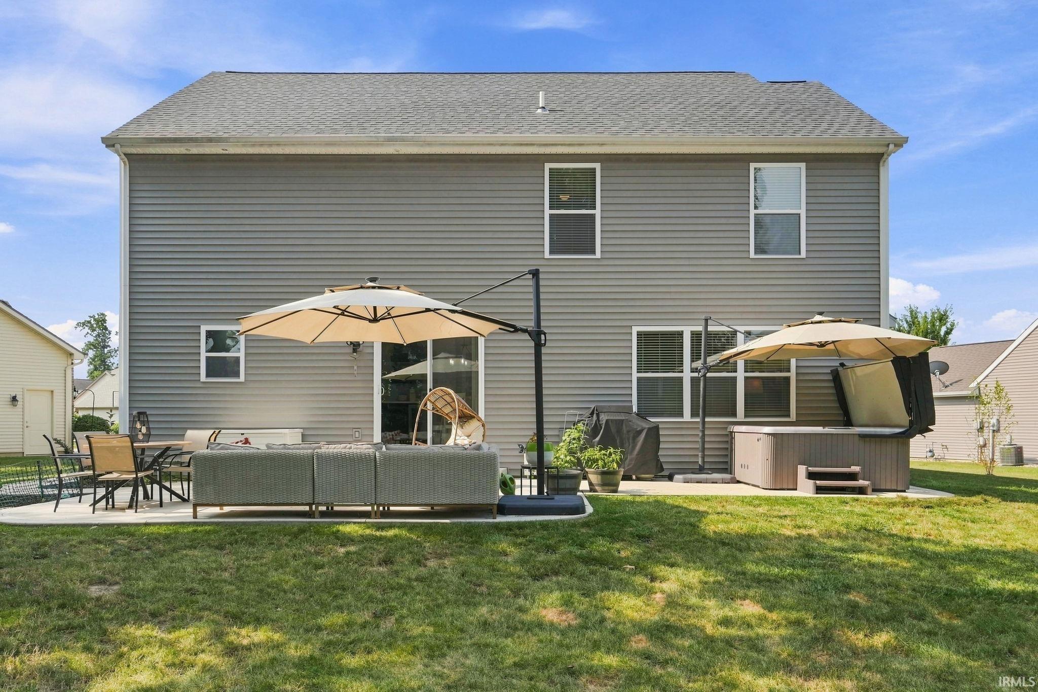 Rear exterior featuring gray horizontal siding, a gray shingled roof, multiple windows, and a sliding glass door